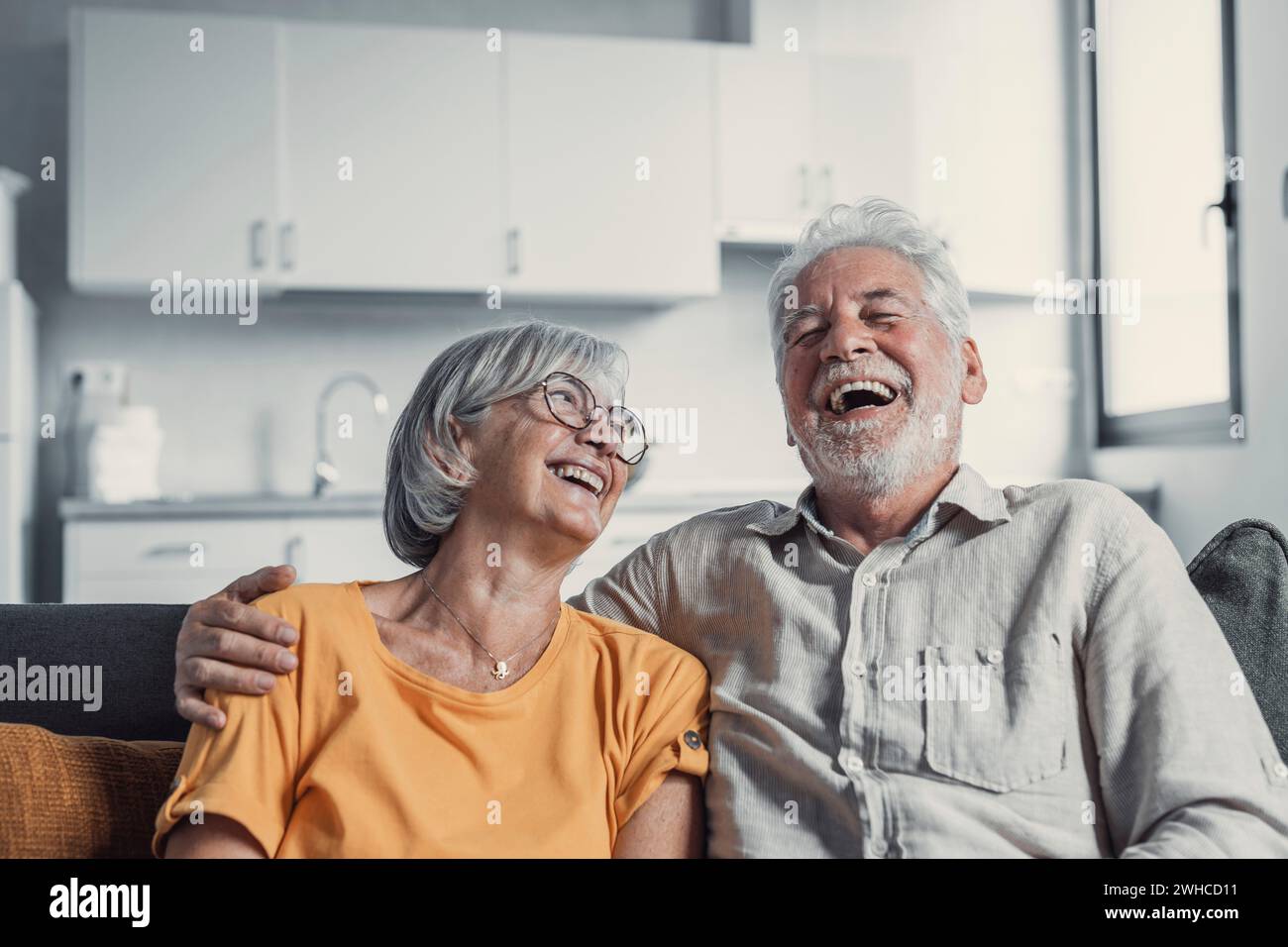 Un mari et une femme heureux et mûrs s'assoient sur le canapé à la maison pour se serrer et se câliner, montrer de l'affection, sourire un couple épris senior se détendre sur le canapé s'amuser, profiter d'un week-end familial romantique et tendre ensemble Banque D'Images