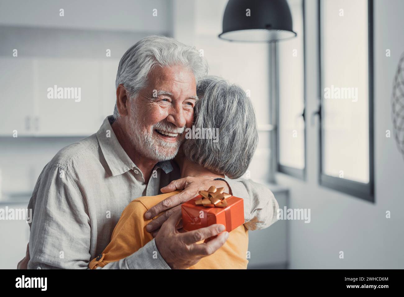 Femme âgée mûre souriante souriante donnant une boîte-cadeau emballée au vieux mari souriant des années 80, félicitant avec anniversaire ou anniversaire de mariage. Joyeux homme senior se sentant excité d'obtenir un cadeau de la femme Banque D'Images