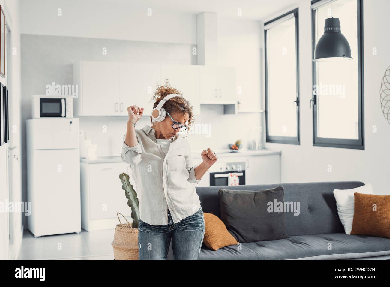 La jeune fille milléniale ravie portant des écouteurs s'amuse à écouter de la musique se détendre dans le salon, jeune femme heureuse dans les écouteurs dansent profiter du week-end de loisirs à la maison, concept sans stress Banque D'Images