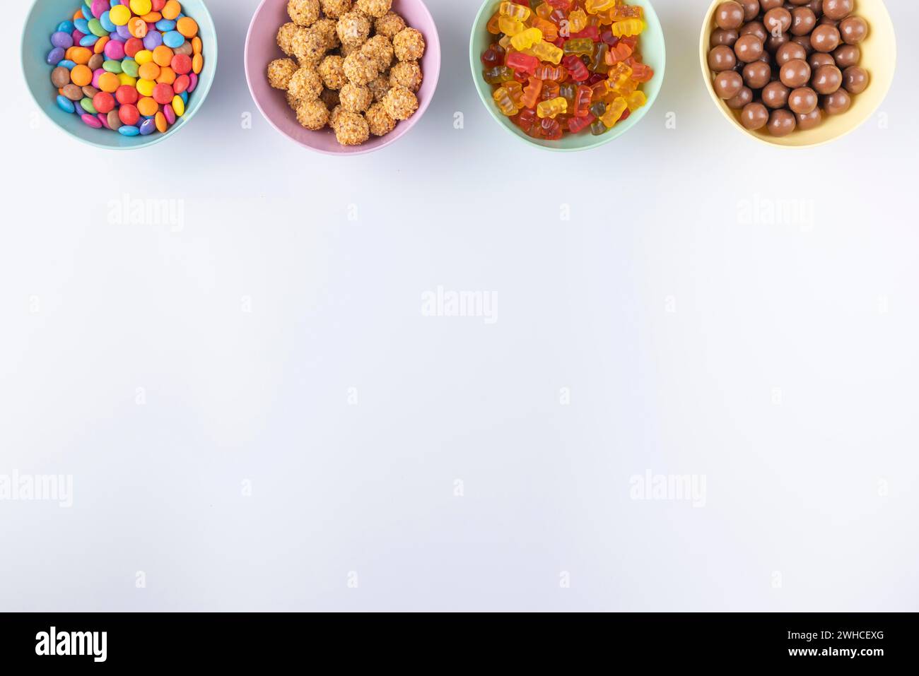 Bols de bonbons colorés sur un fond clair, disposés au bord de l'image Banque D'Images
