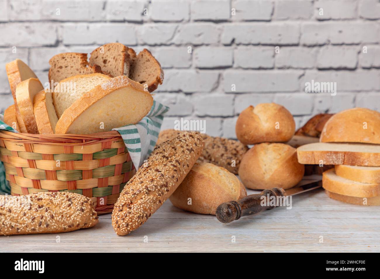 Divers pains complets et blancs dans un panier à pain sur un plan de travail de style campagnard Banque D'Images