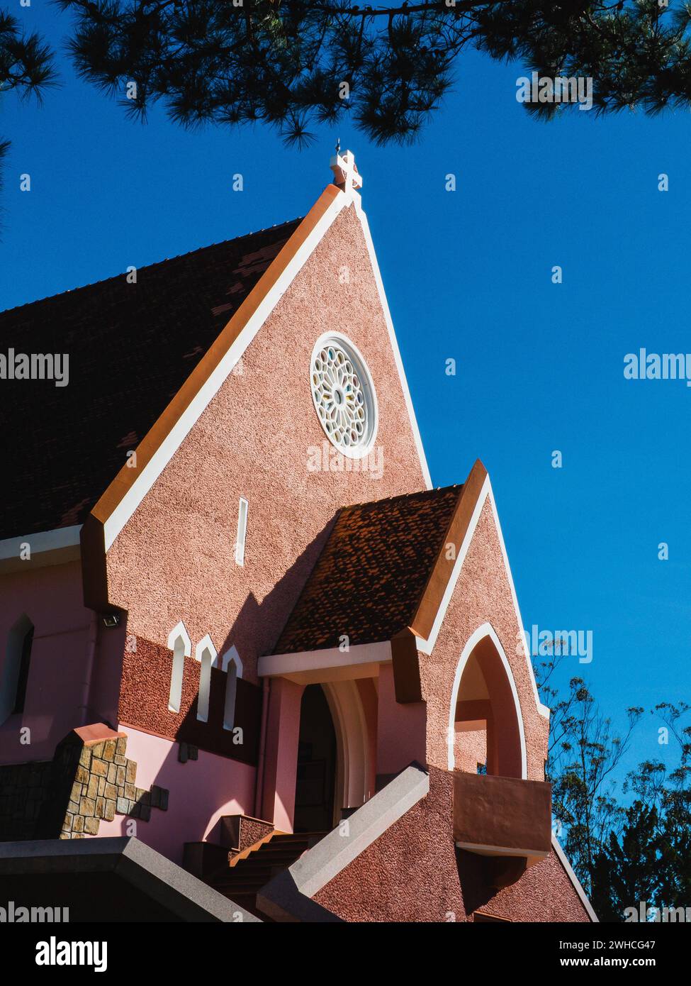 Diocèse de l'église du domaine de Marie sur fond de ciel bleu, caché derrière des branches de pin le jour ensoleillé, situé à Da Lat, province de Lam Dong, Vietnam. Banque D'Images