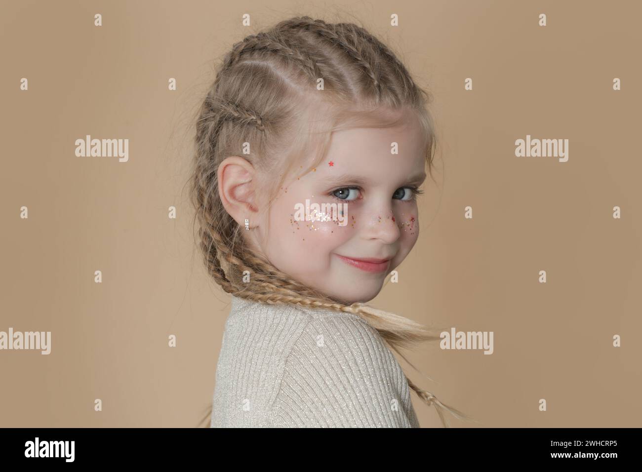 Portrait de petite fille blonde mignonne avec des tresses de boxeur et des paillettes om visage Banque D'Images