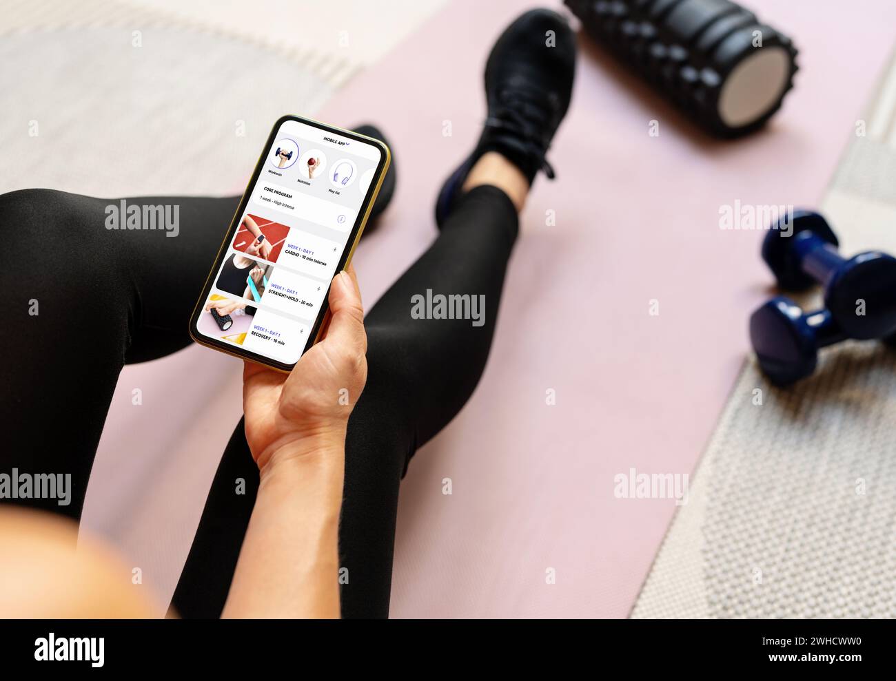 Femme utilise une application de fitness mobile sur son smartphone. Assistant sportif numérique en ligne. Banque D'Images