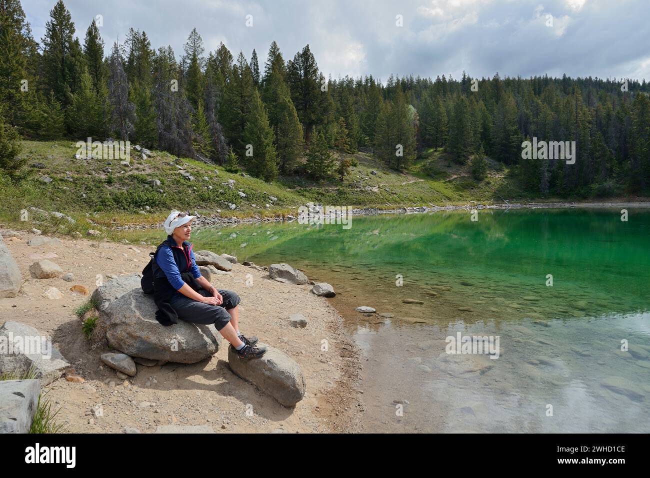 Randonneur reposant sur un rocher au bord d'un lac, Vallée des cinq lacs, Parc national Jasper, Alberta, Canada Banque D'Images