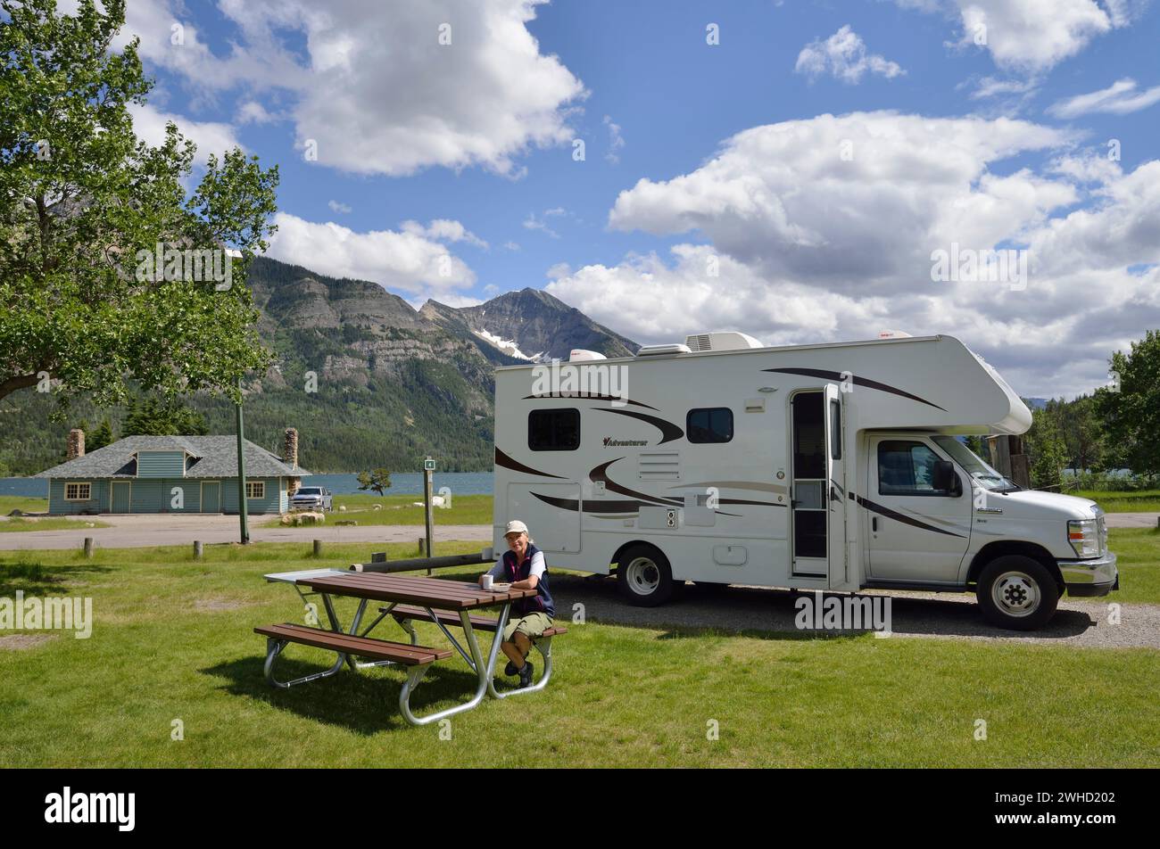 Femme assise devant un campeur au terrain de camping Waterton Townsite, parc national des Lacs-Waterton, Alberta, Canada Banque D'Images