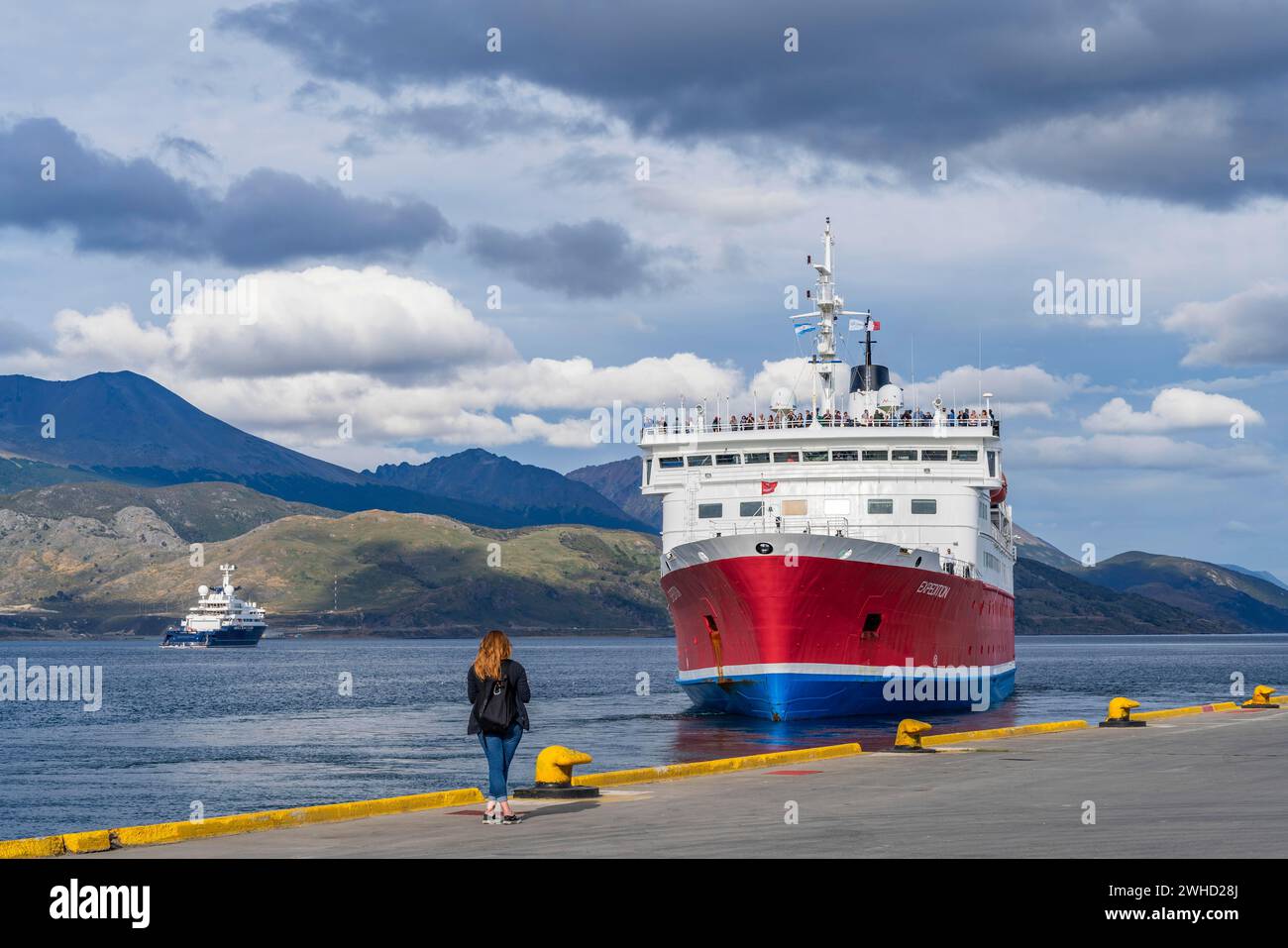 Une femme regarde un navire de croisière nommé Expedition partir du port du canal Beagle, Ushuaia, île de Terre de feu, Patagonie, Argentine Banque D'Images