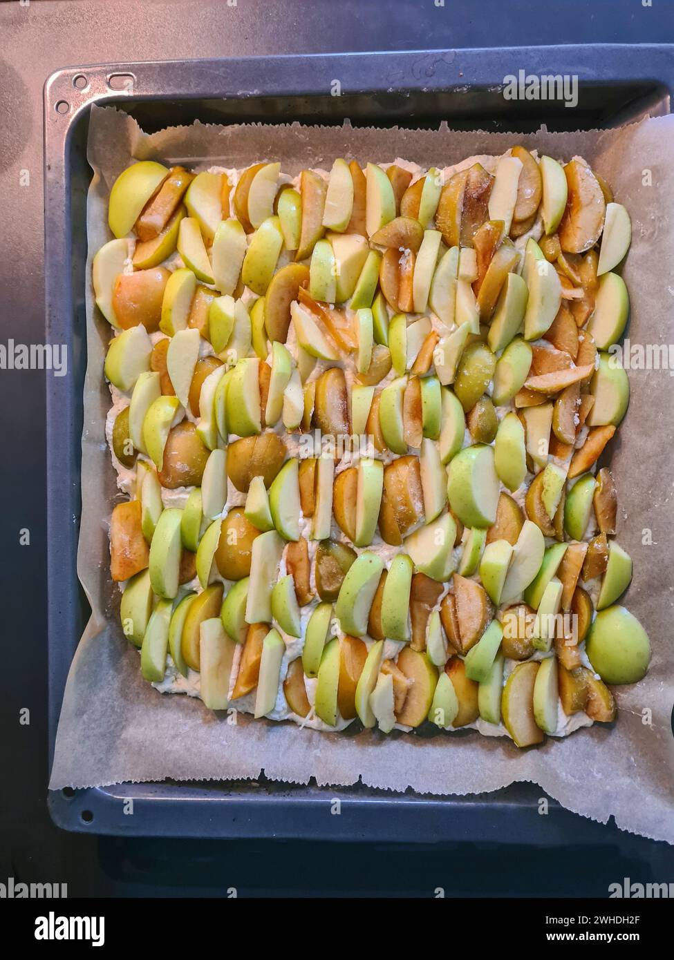 Gâteau en feuille avec des pommes coupées en deux sur du papier sulfurisé en préparation pour la cuisson d'une tarte aux pommes Banque D'Images