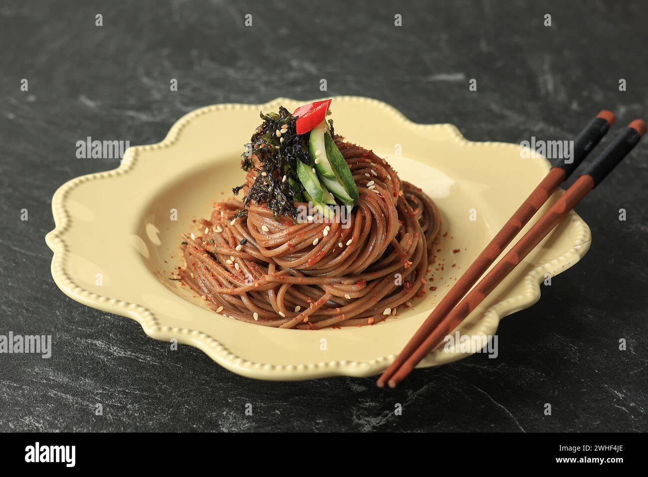 Salade coréenne de nouilles au sarrasin Memil Makguksu sur une assiette en céramique crème. Nouilles somen épicées pour Bibim Guksu. Banque D'Images