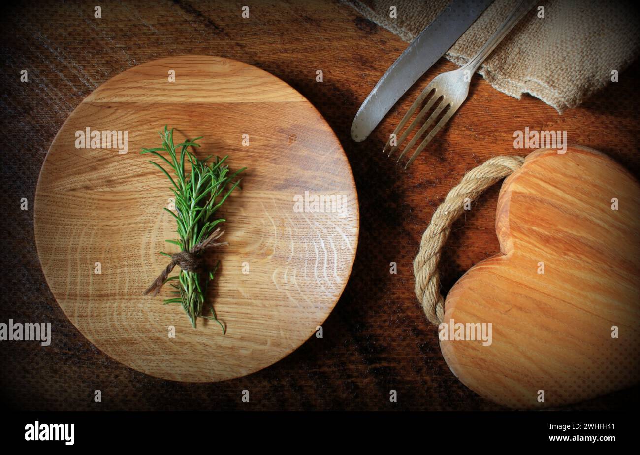 Argenterie vintage, planche à découper, assiette, romarin sur fond de bois rustique. Vue de dessus de la table de réglage de la cuisine Banque D'Images