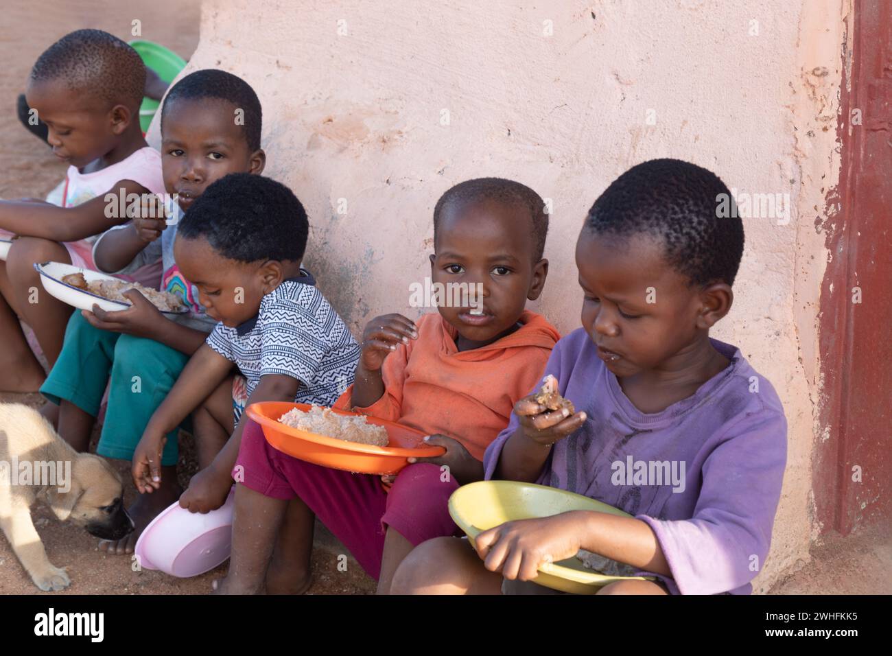 Groupe d'enfants africains de village mangeant dans la cour, famine et malnutrition ONG résolvant des problèmes mondiaux Banque D'Images