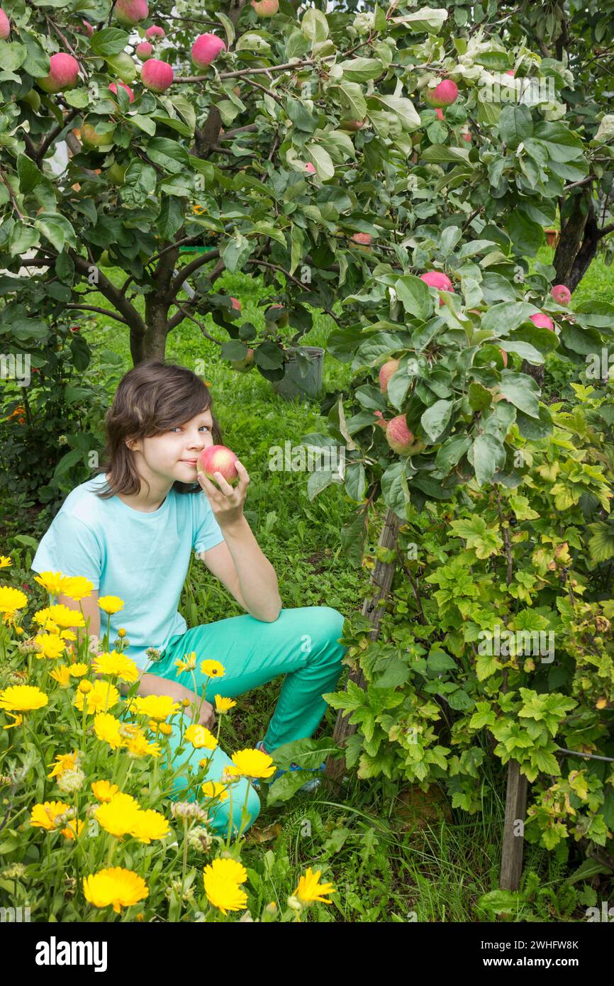 Girlie inspire l'arôme d'une pomme, assis dans le jardin Banque D'Images