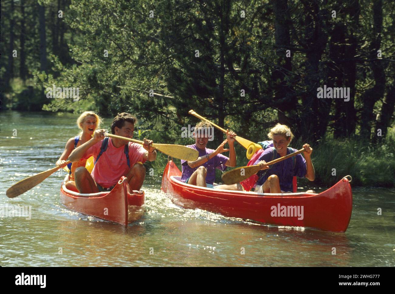 de jolis jeunes amis de cheveux blonds pagayant sur une rivière avec canoo regardant la caméra avant et jouant avec l'eau zénitude paysage vert feuillage arrière-plan Banque D'Images