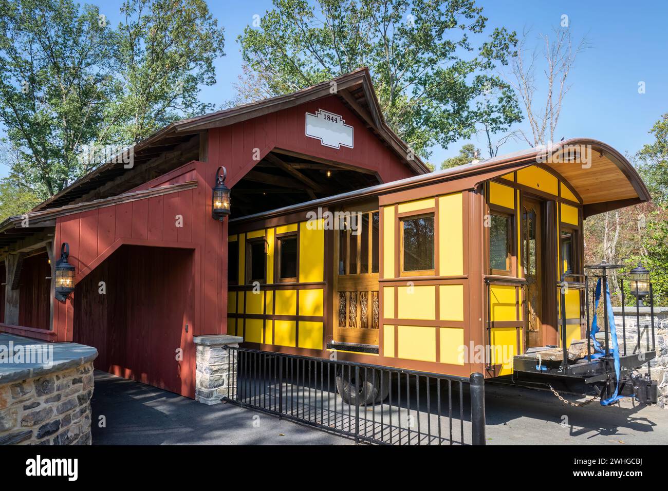 Installation d'une nouvelle voiture jaune Antique Passenger à travers un pont de couverture sur une voie ferrée Banque D'Images