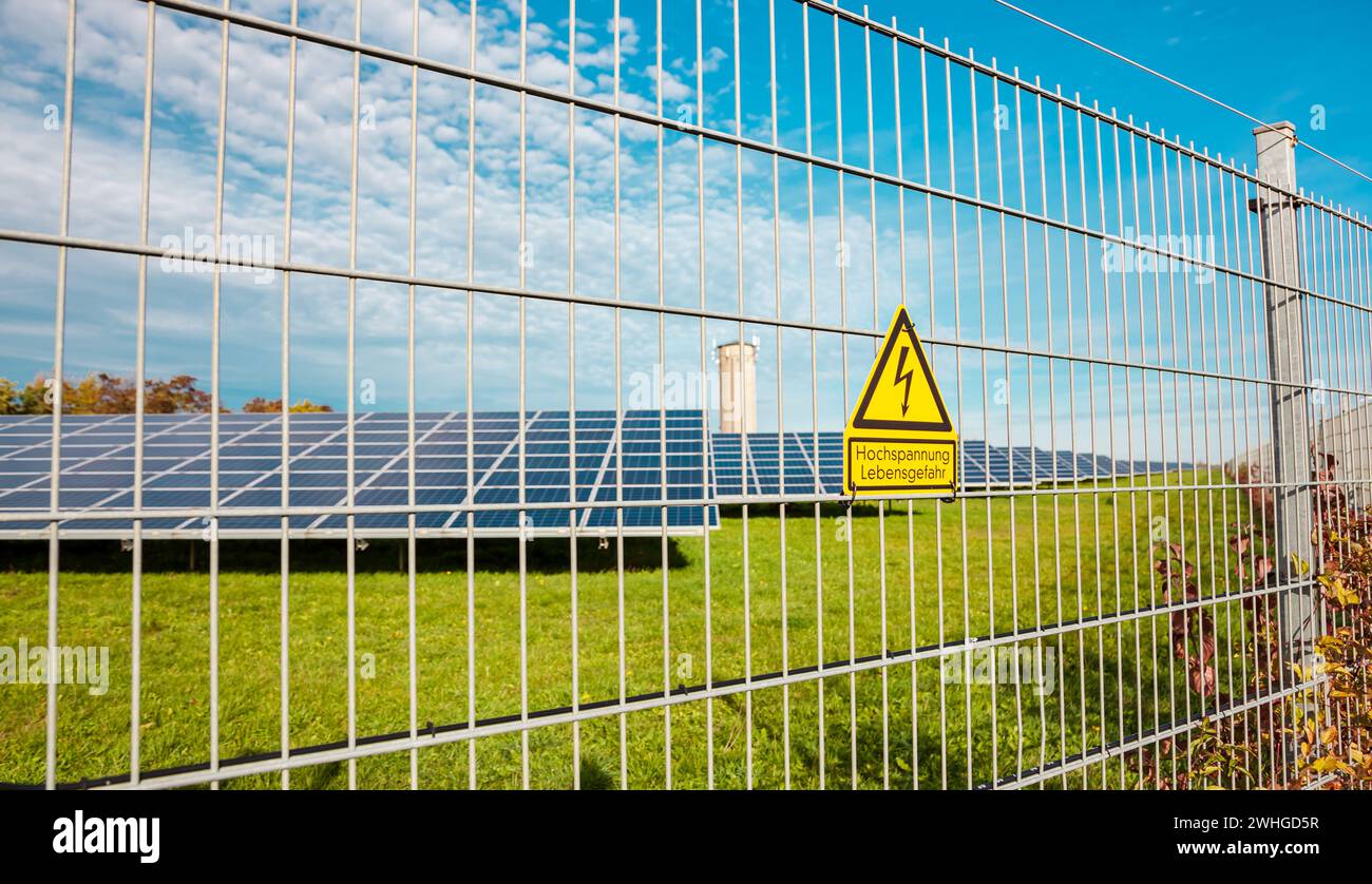 Signe d'avertissement de haute tension danger sur la clôture électrique extérieure. centrale solaire. Banque D'Images