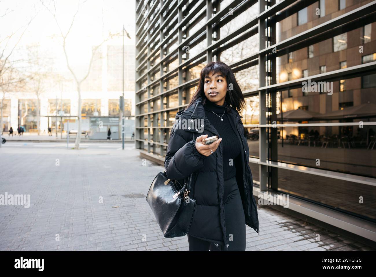 Jeune belle femme, vêtue de vêtements noirs, marchant dans les rues d'une grande ville. Banque D'Images