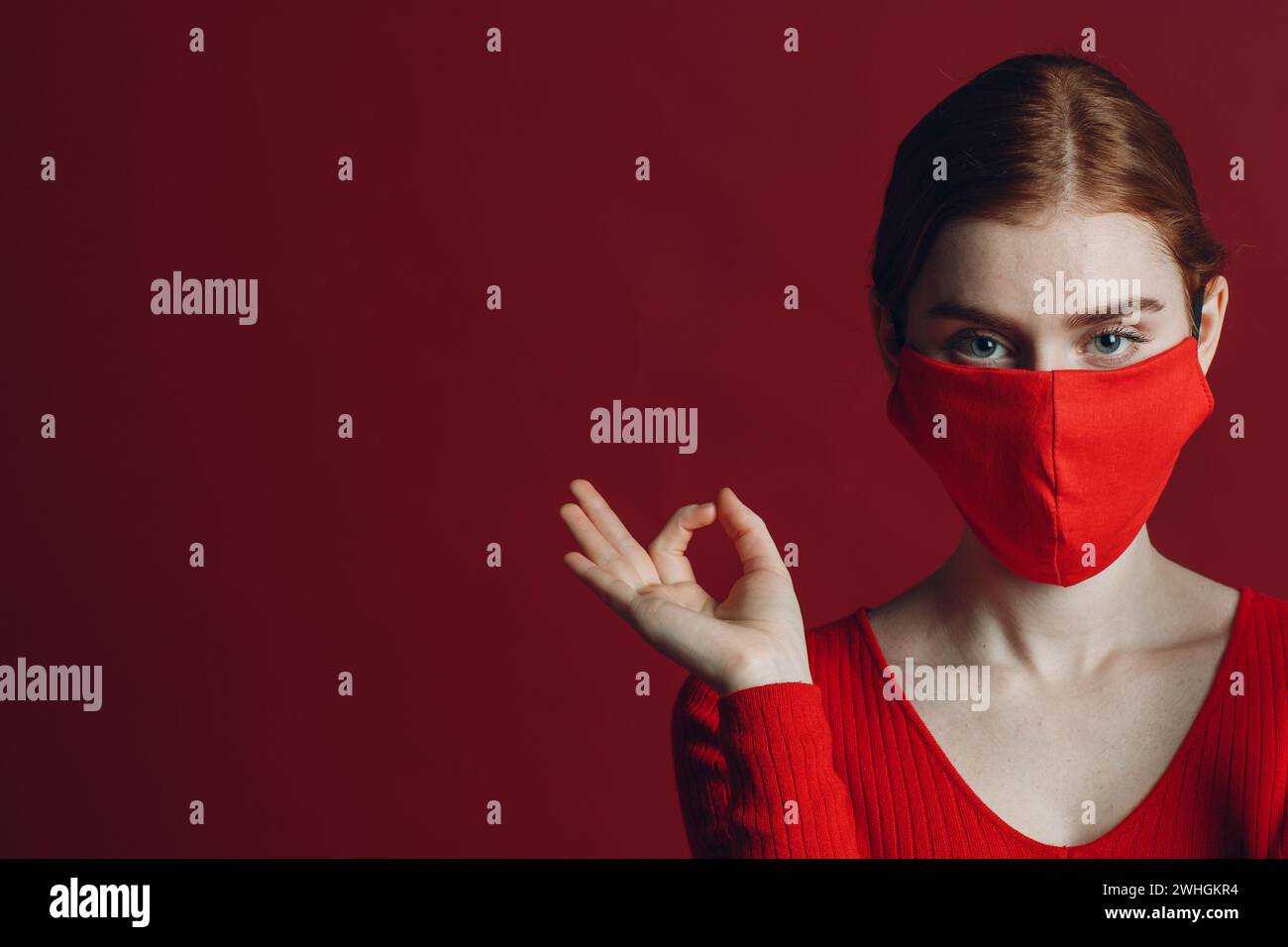 Studio portrait de la jeune femme dans un masque médical protecteur isolé sur fond rouge.Yoga, calme, zen et méditation a covi Banque D'Images