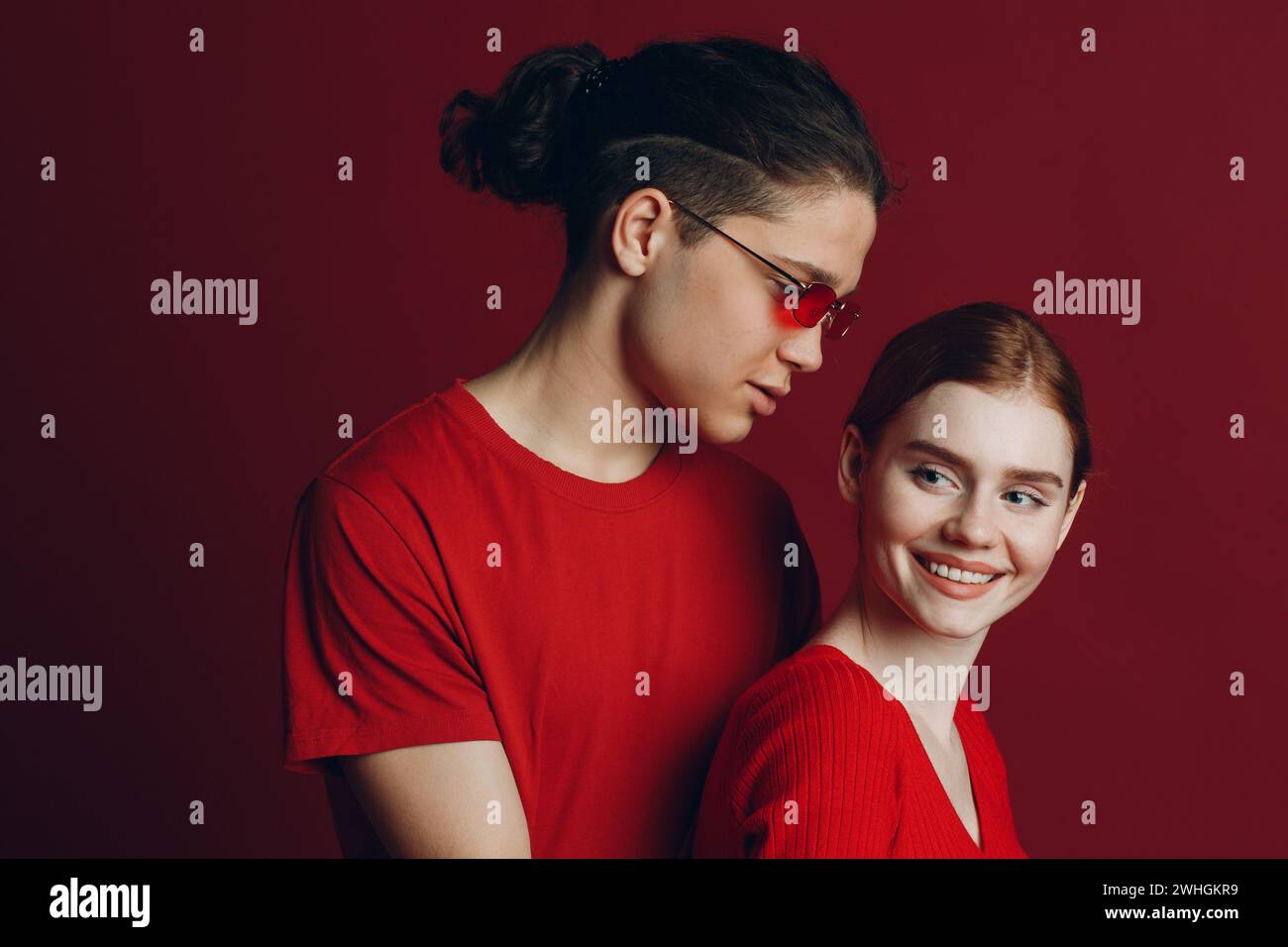 Beau jeune couple souriant enserre sur fond rouge. Concept de la Saint-Valentin. Banque D'Images