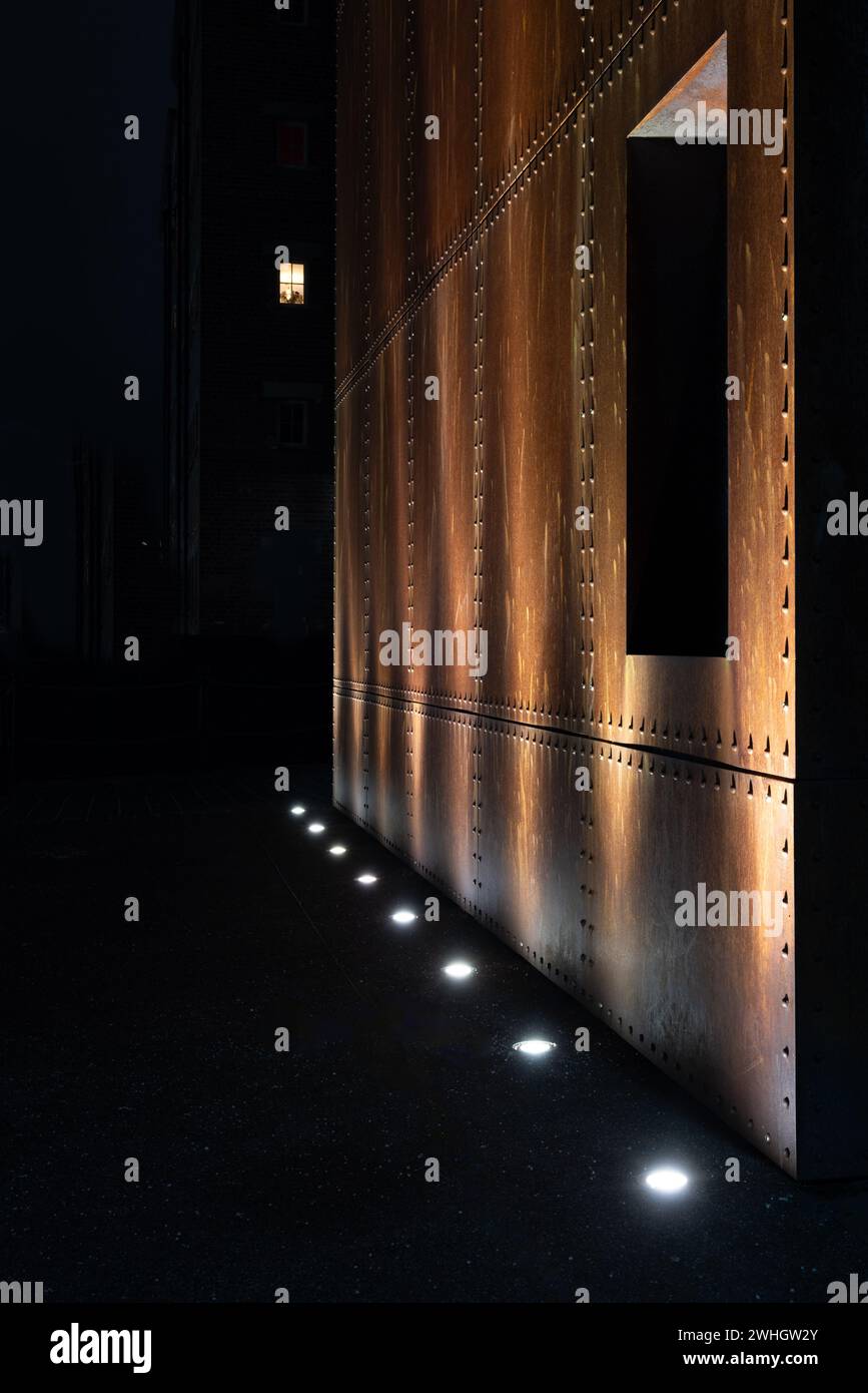 Un mur en métal industriel rouillé éclairé par des lampes lumineuses Banque D'Images