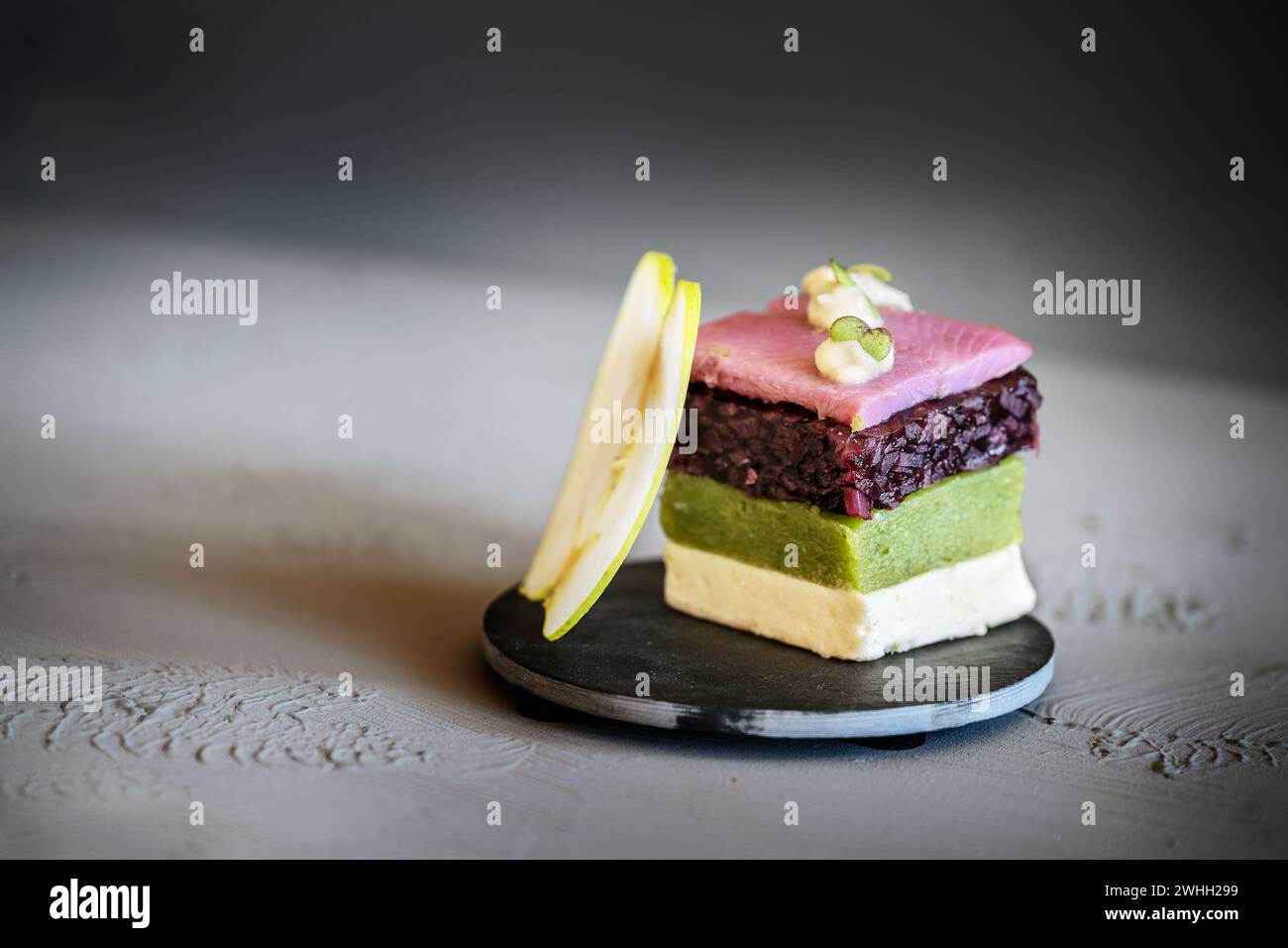 Hors-d'œuvre de poisson, plat en couches de hareng posé rose coupé carré, oignon rouge, concombre, gélatine crème et une tranche de pomme, moder Banque D'Images