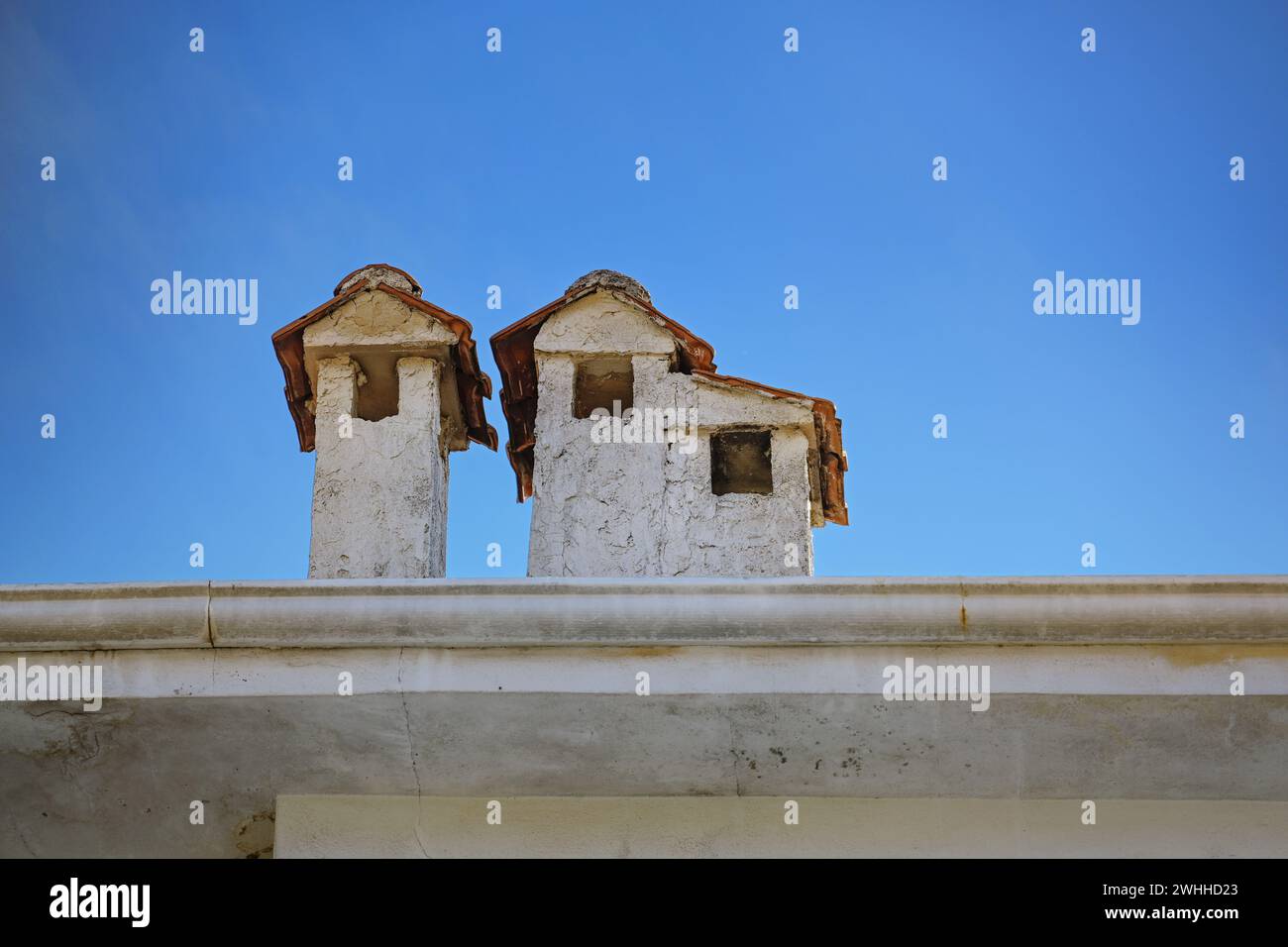 Cheminées plâtrées légères avec des toits en tuiles sur un bâtiment en Grèce, ressemblant à de petites maisons, ciel bleu avec espace de copie, selecte Banque D'Images