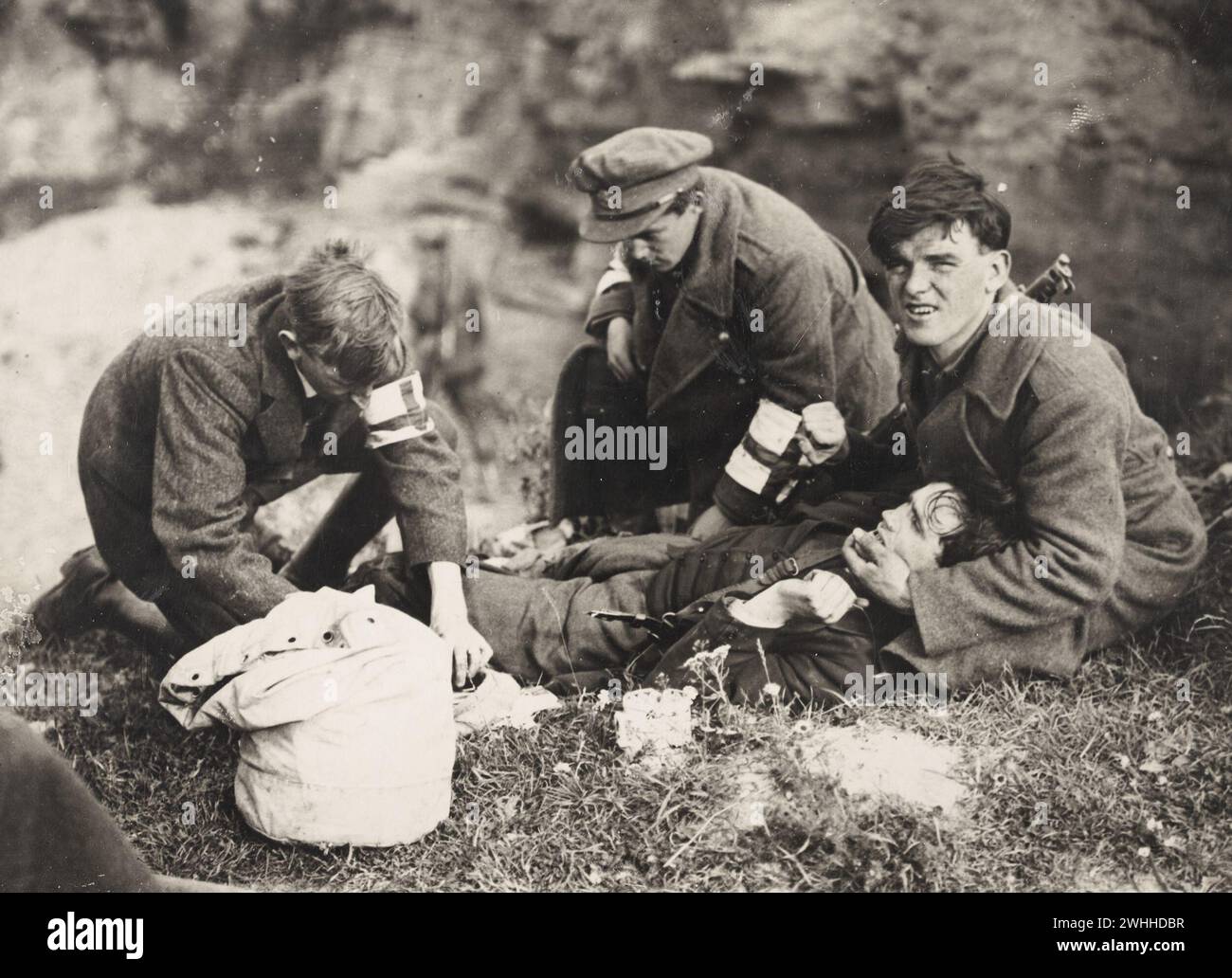 25 juillet 1922 « soldat blessé pris en charge par la Croix-Rouge sur le front sud-ouest pendant la guerre civile irlandaise » ! L'homme blessé semble souffrir énormément et est retenu et réconforté. Brassards de fortune de la Croix-Rouge sur les deux médecins, et le sac de kit à l'ancienne contenant apparemment leurs fournitures de premiers soins! Banque D'Images