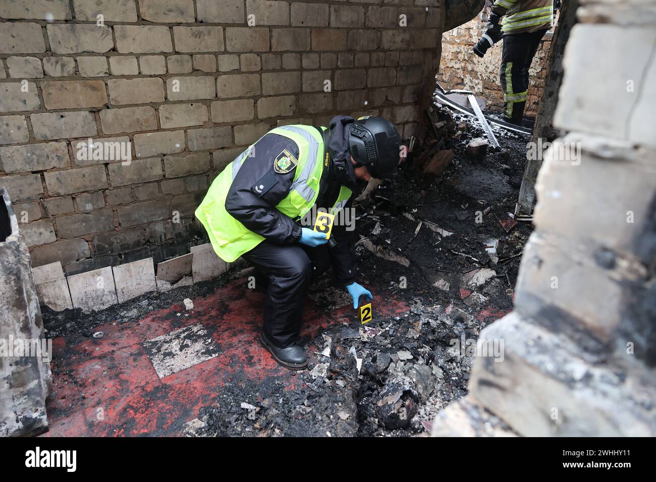 KHARKIV, UKRAINE - 10 FÉVRIER 2024 - Un policier dépose des cartes de numéro de preuve dans une maison où des personnes brûlées vives ont pris feu à la suite de l'attaque d'un drone russe contre un dépôt de pétrole dans le district de Nemyshlianskyi, Kharkiv, dans le nord-est de l'Ukraine. Comme indiqué, sept civils, dont trois enfants, ont été tués et au moins 57 personnes ont été blessées dans la dernière frappe de drone kamikaze Shahed de Russie sur Kharkiv dans la nuit de samedi 10 février. Les Russes ont lancé près de 10 drones, dont huit ont été interceptés. Trois drones ont frappé le district de Nemyshlyansky endommageant un dépôt de pétrole et provoquant une fue Banque D'Images