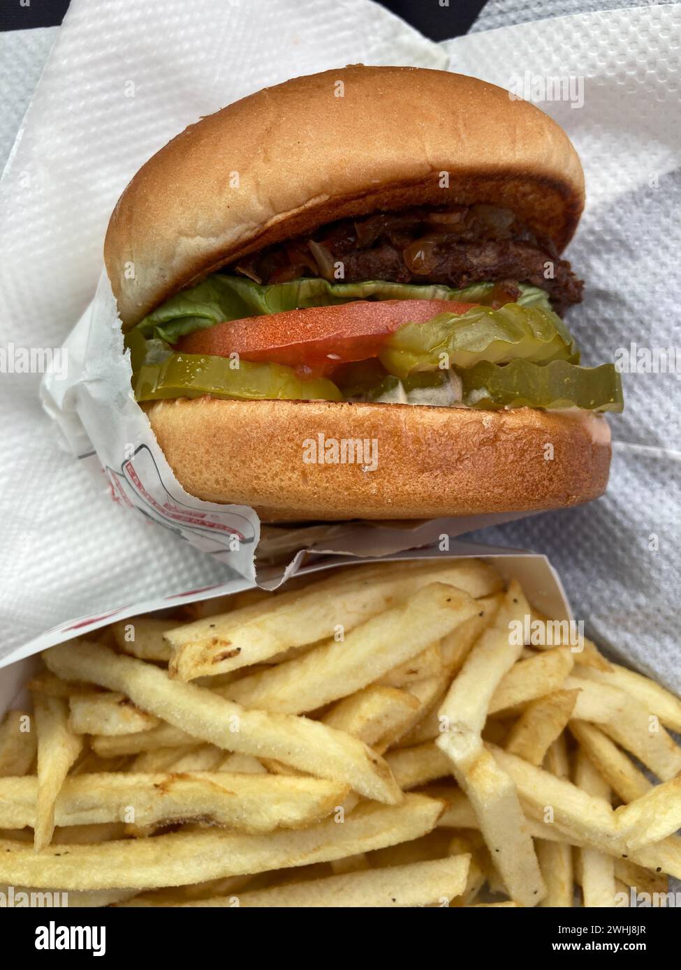 Hamburger de restauration rapide avec tomate, laitue, cornichons et accompagnement de frites au drive-in en Californie, aux États-Unis d'Amérique. Repas entièrement américain. Banque D'Images