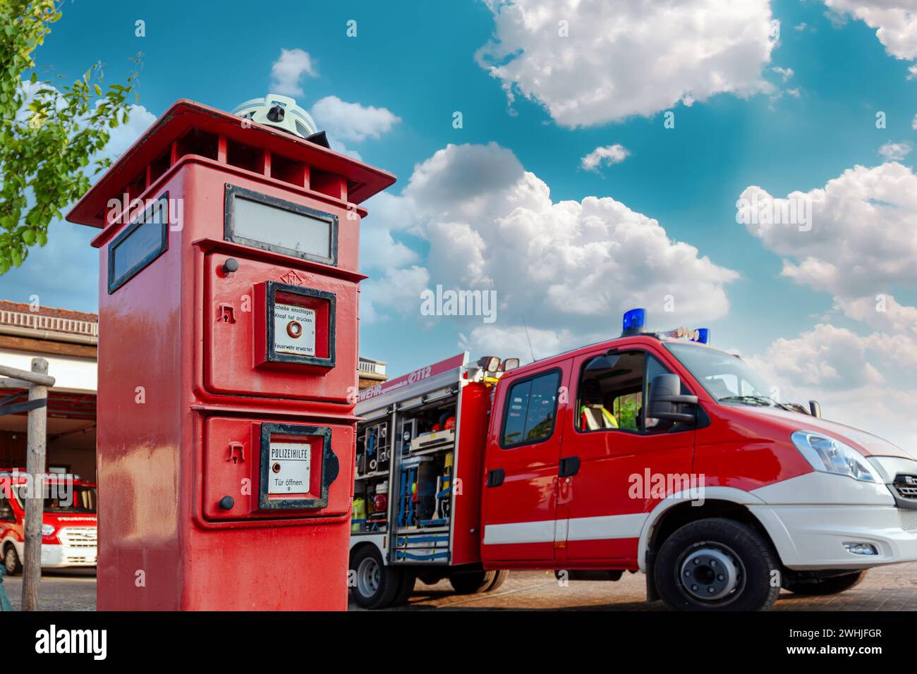 Casque blanc d'un pompier allemand sur pompier, colonne de bouton d'urgence de police et camion de pompier Banque D'Images