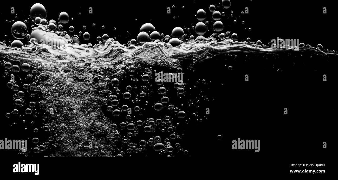 Bulles d'eau de soude éclaboussant sous l'eau sur fond noir. Texture liquide de soude qui pétille et flotte jusqu'à la surface comme une explosion dans l'UEDN Banque D'Images