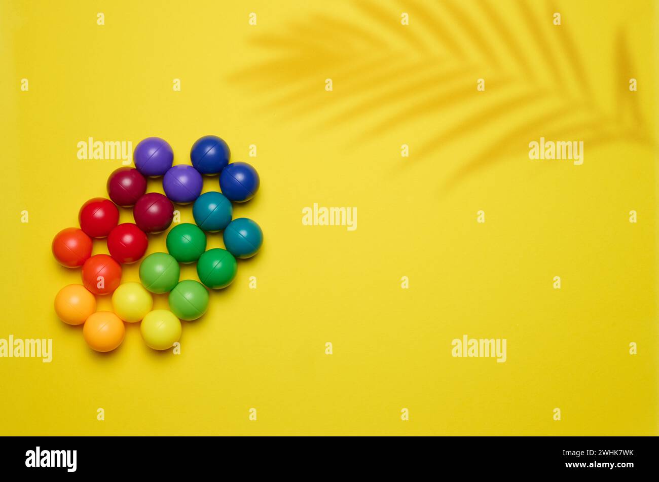 Fond abstrait avec des boules en plastique multicolores sur un fond jaune, une scène pour la démonstration de cosmétiques et de prod Banque D'Images
