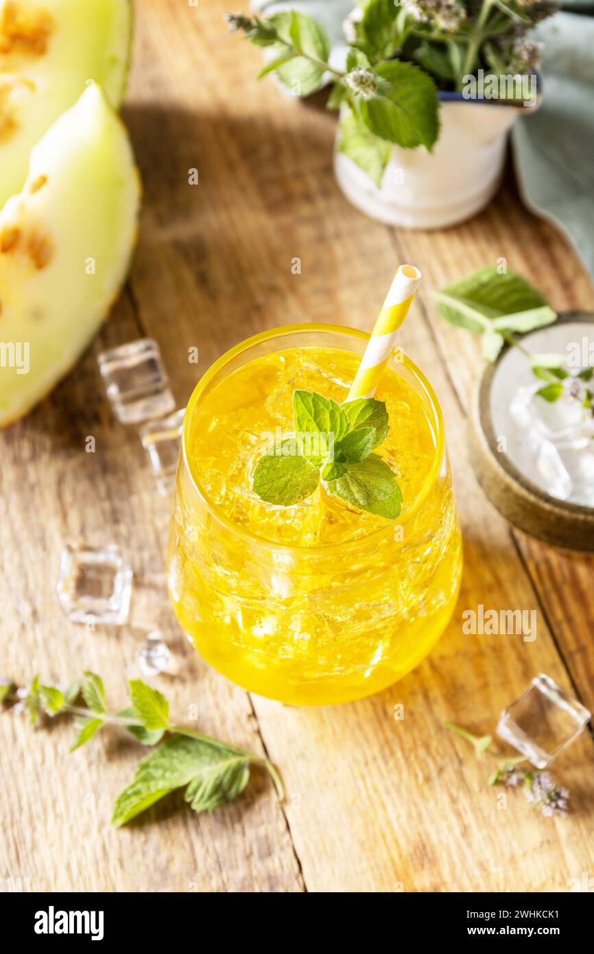 Limonade de melon dans des verres avec de la glace et de la menthe sur une table rustique en bois. Boisson d'été fruitée fraîche et rafraîchissante, boissons saisonnières. Banque D'Images