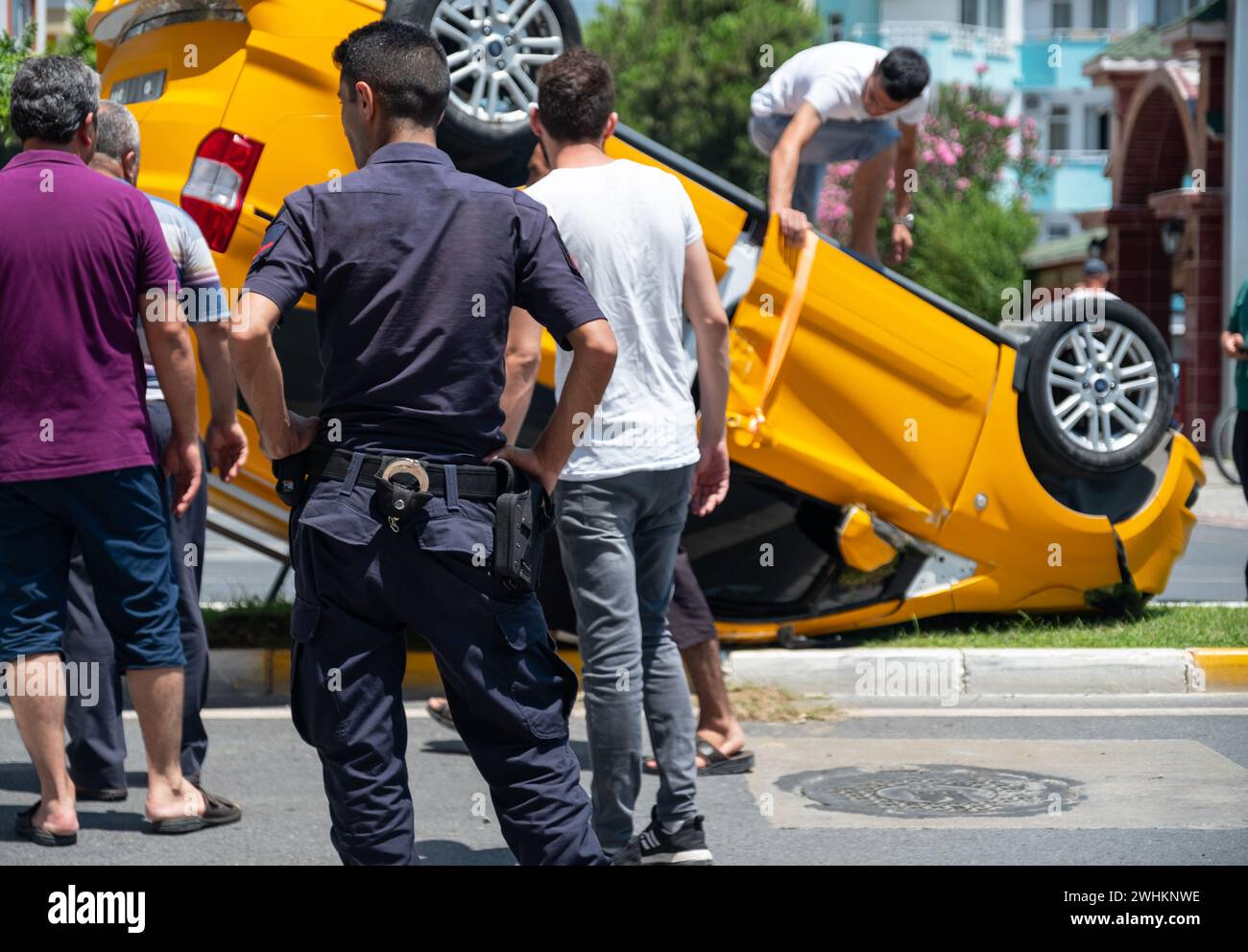 Homme de police debout devant une voiture qui s'est rabattie le milieu de la rue dans de mauvaises circonstances Banque D'Images