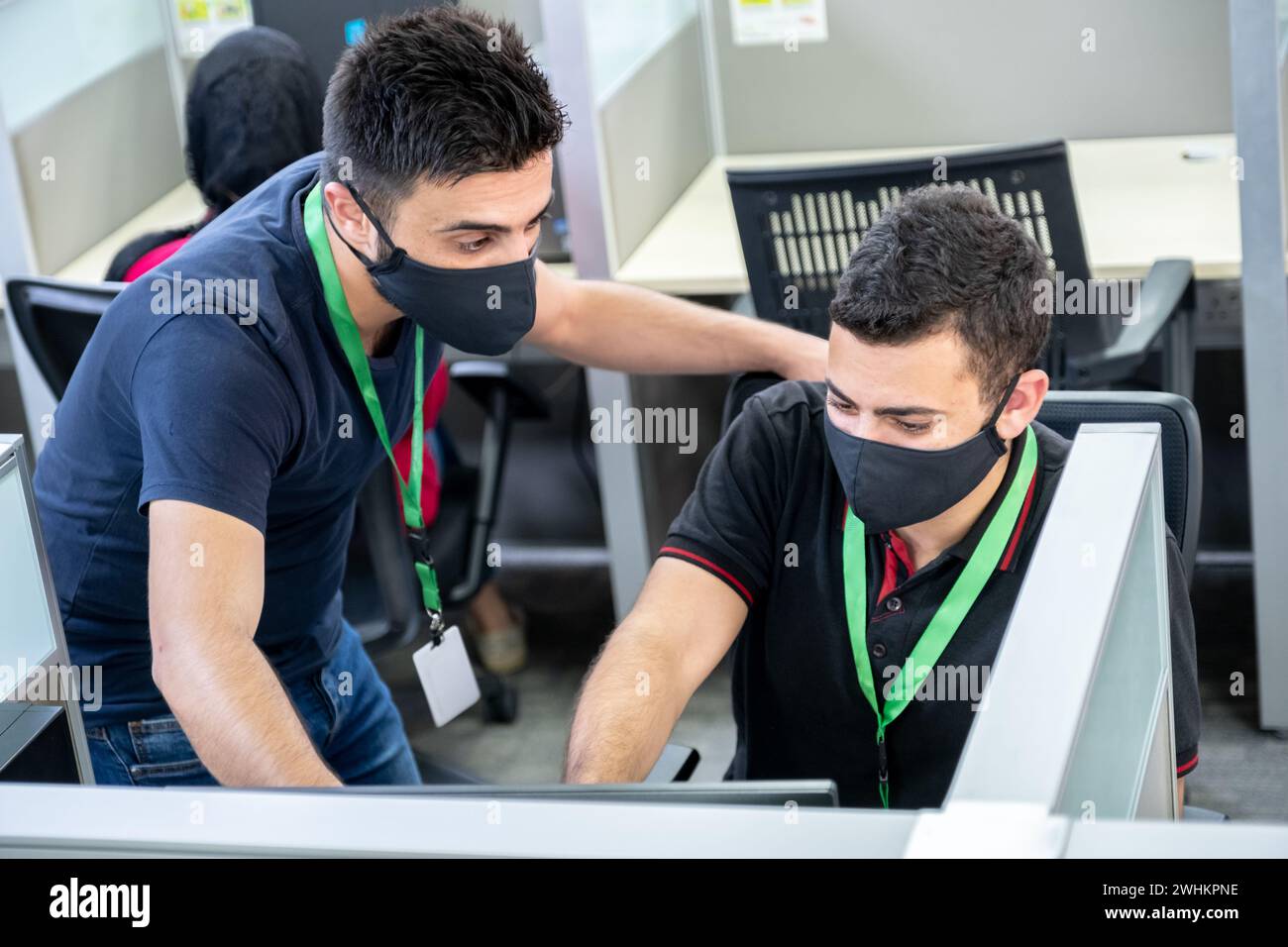 Chef d'équipe dans le travail soutenant le nouveau junior pendant ils portent des masques Banque D'Images