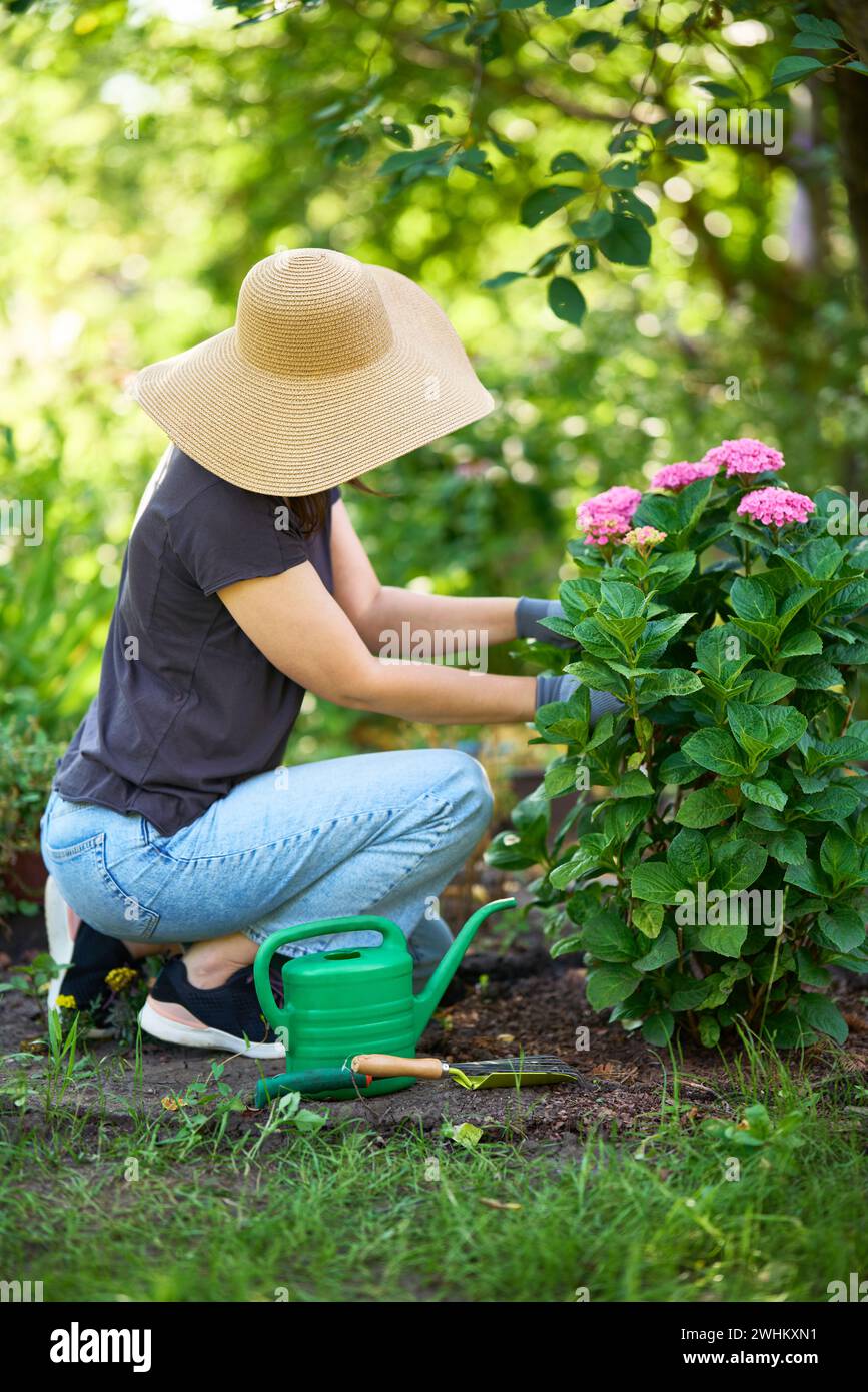Jardinière femme en chapeau et gants plante des fleurs sur le jardin. Jardinage et floriculture Banque D'Images