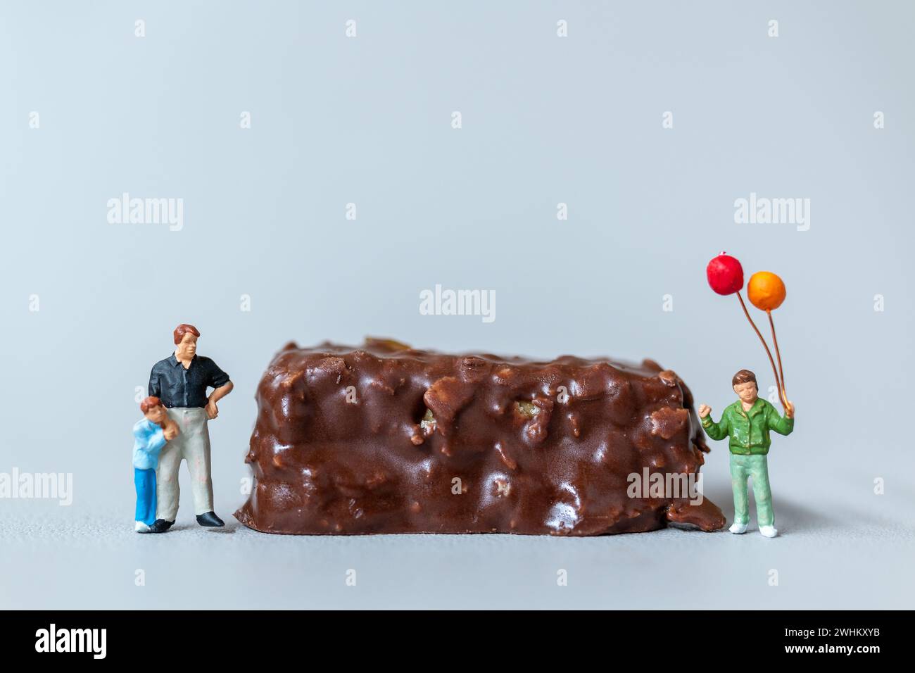 Enfants avec des barres de chocolat debout sur fond gris. Concept de la Journée mondiale du chocolat Banque D'Images