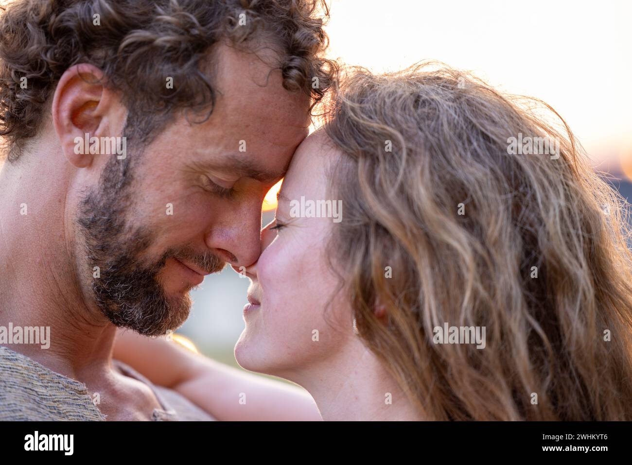 Jeune couple amoureux s'embrasse sur un fond de coucher de soleil naturel Banque D'Images