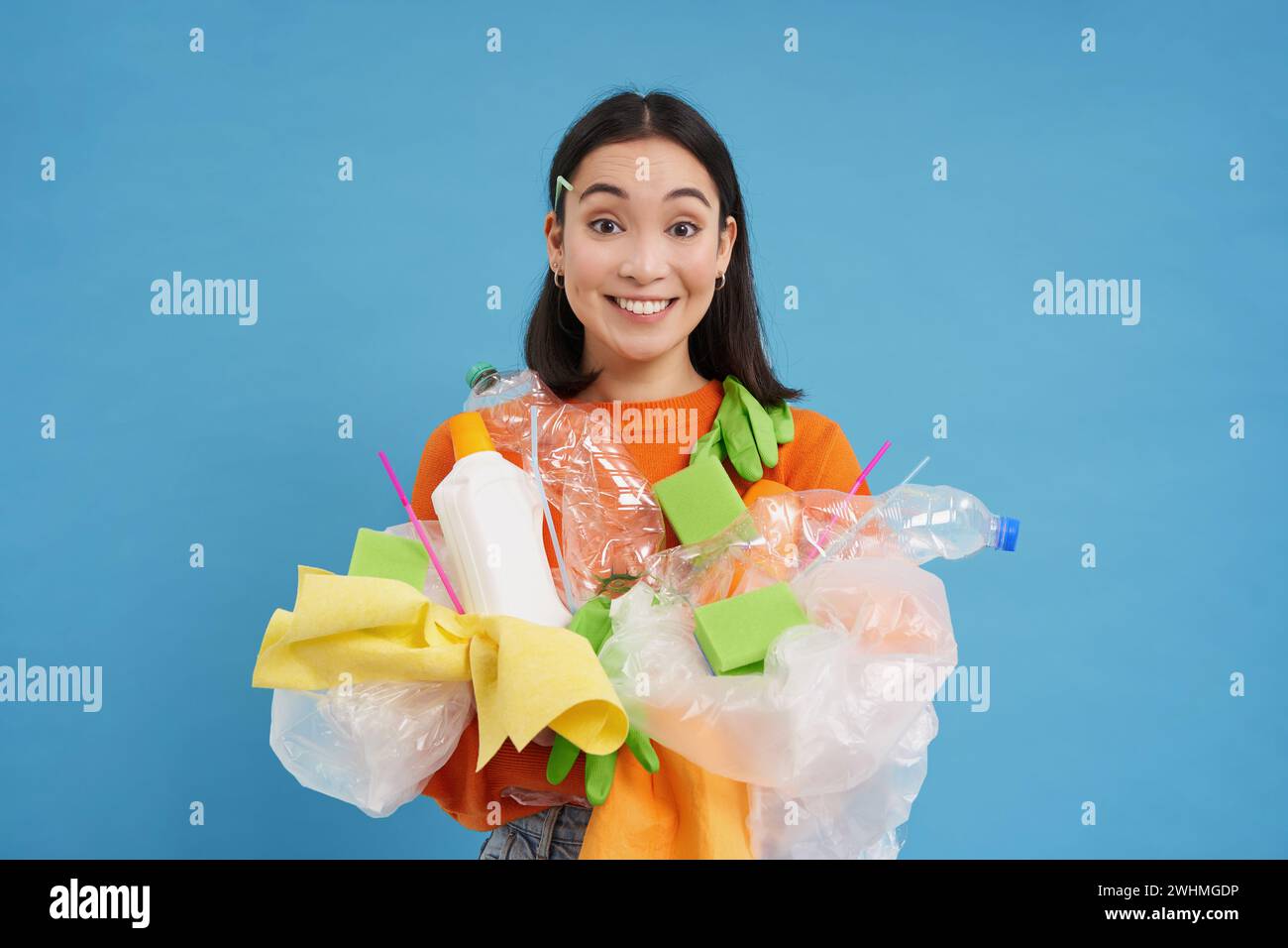 Femme coréenne souriante, recyclant, tenant les déchets en plastique et les triant pour le centre de recyclage, fond bleu Banque D'Images