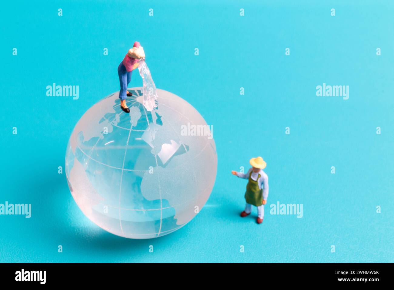 Globe en cristal de nettoyage de personnes miniatures sur fond bleu Banque D'Images