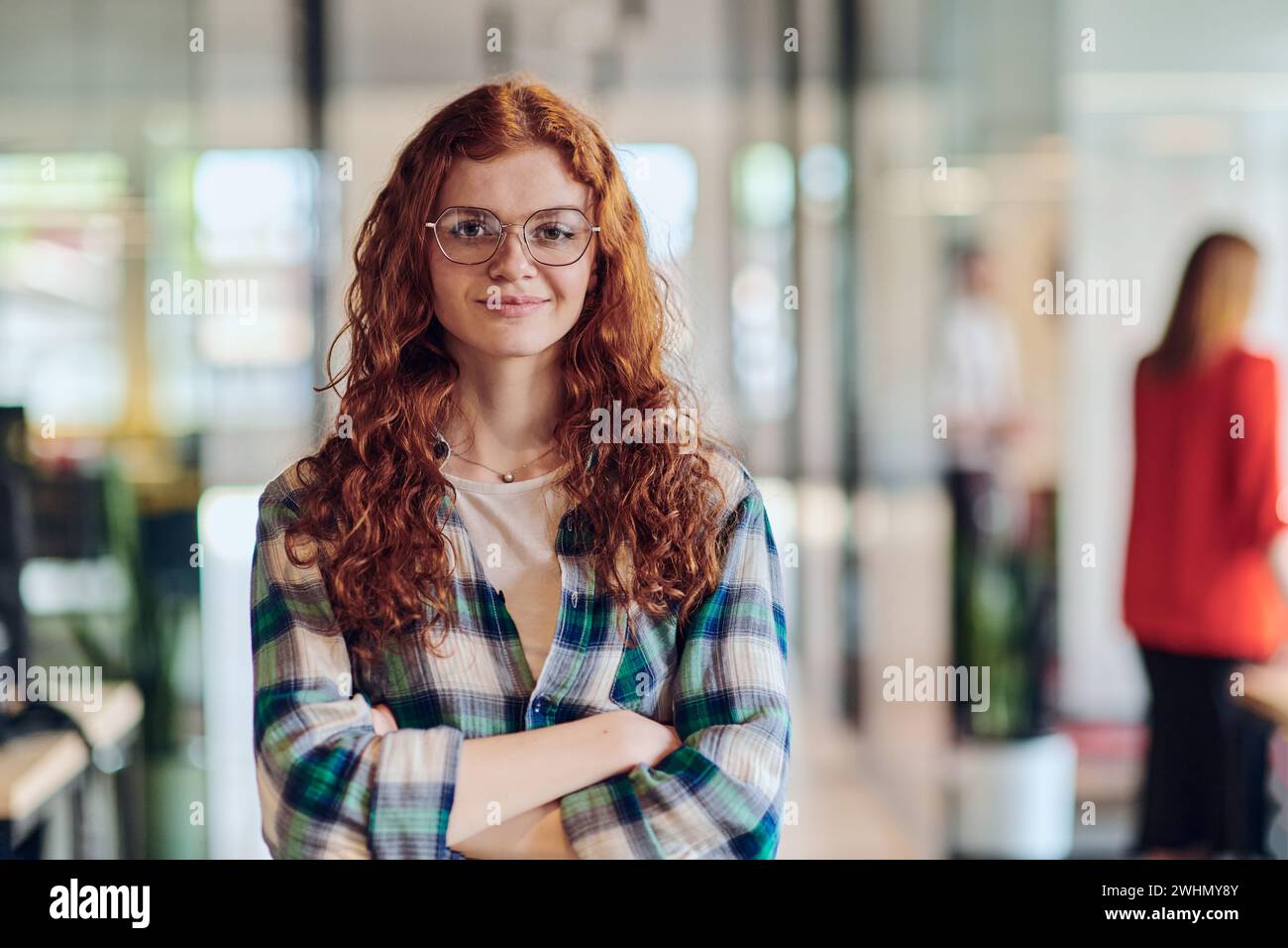 Le portrait d'une jeune femme d'affaires aux cheveux orange modernes capture sa présence bien serrée dans le couloir d'une startup contemporaine Banque D'Images