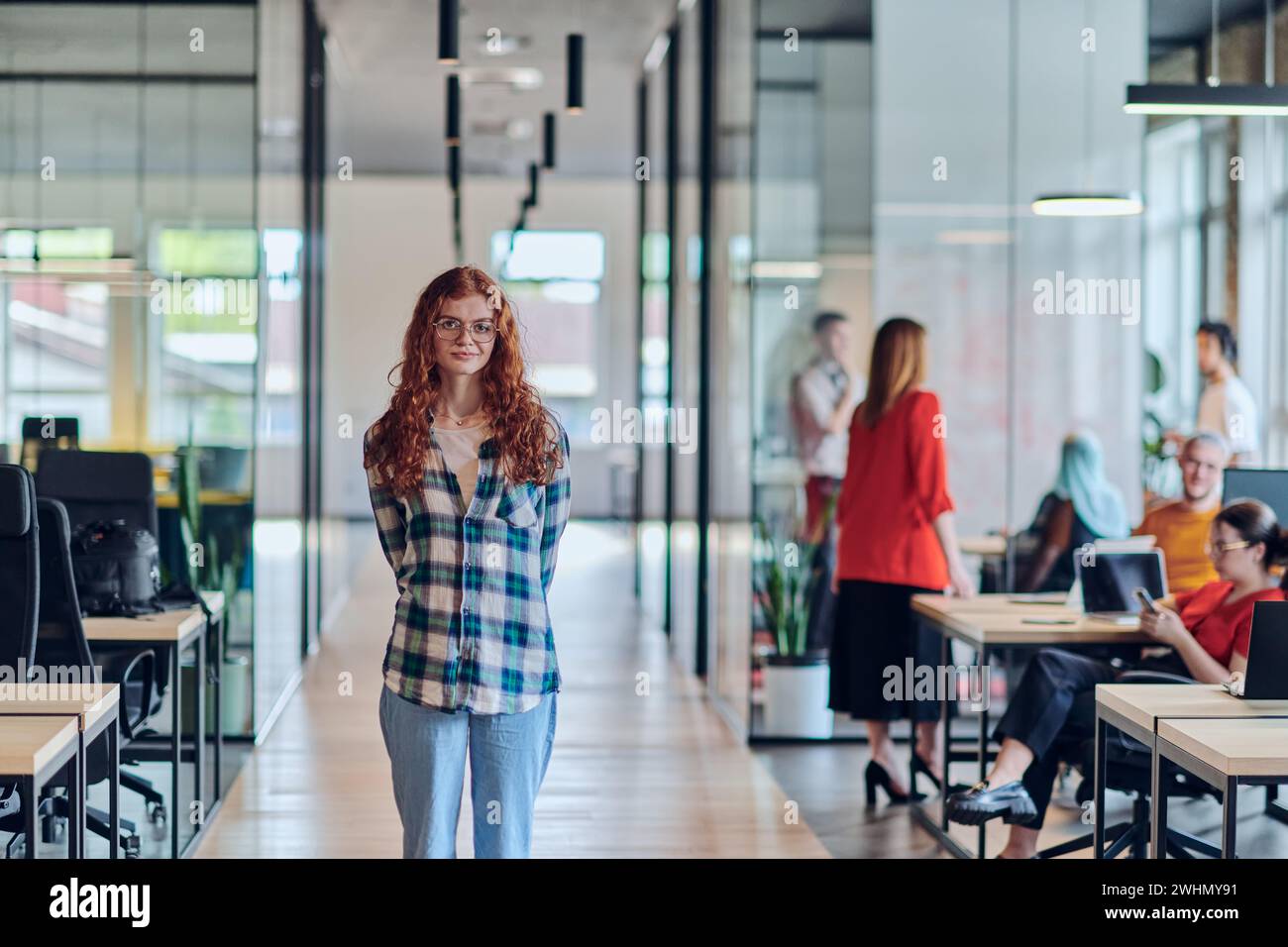 Le portrait d'une jeune femme d'affaires aux cheveux orange modernes capture sa présence bien serrée dans le couloir d'une startup contemporaine Banque D'Images