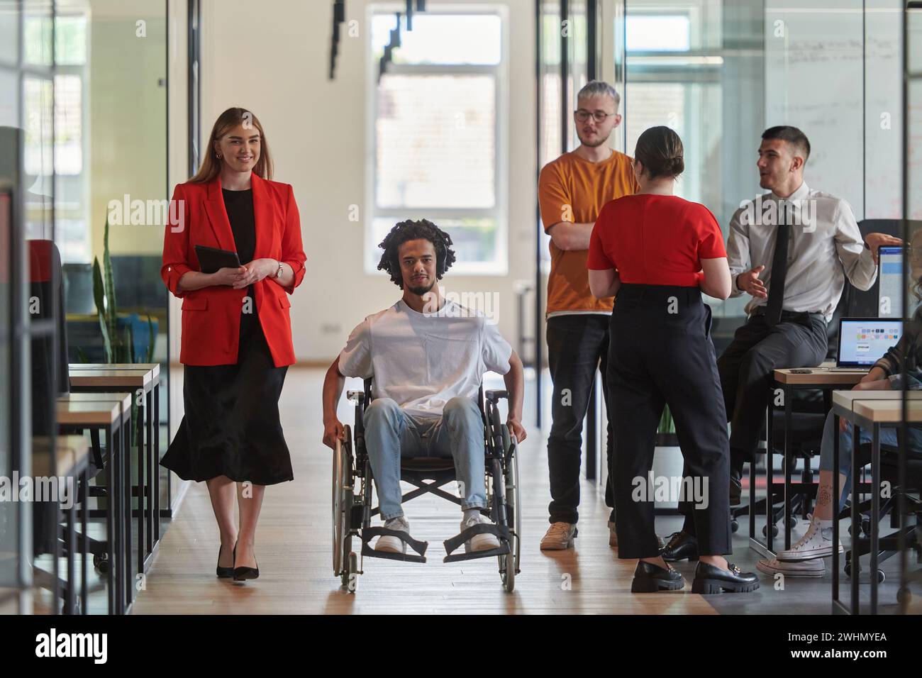 Un groupe de jeunes gens d'affaires dans un bureau moderne vitré capture l'essence de la diversité et de la collaboration, tandis que deux Banque D'Images