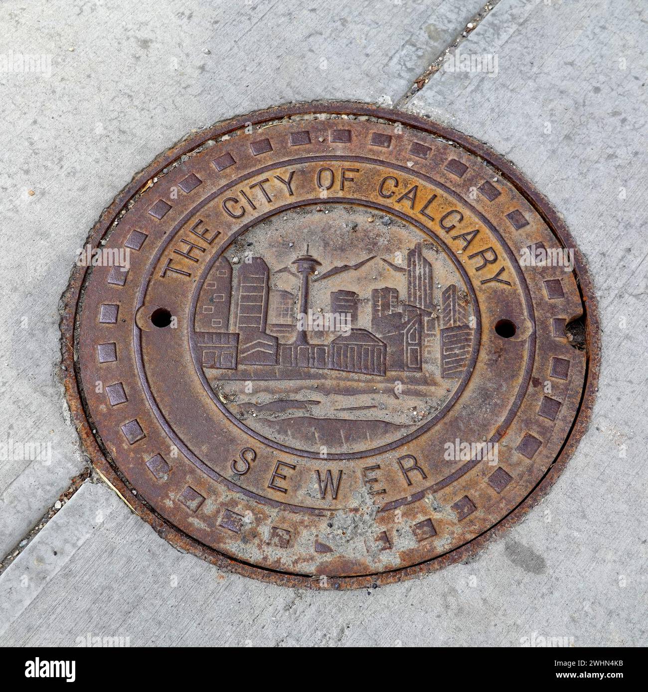 Un couvercle décoratif d'égout en fonte sur un trottoir à Calgary, Alberta, Canada Banque D'Images