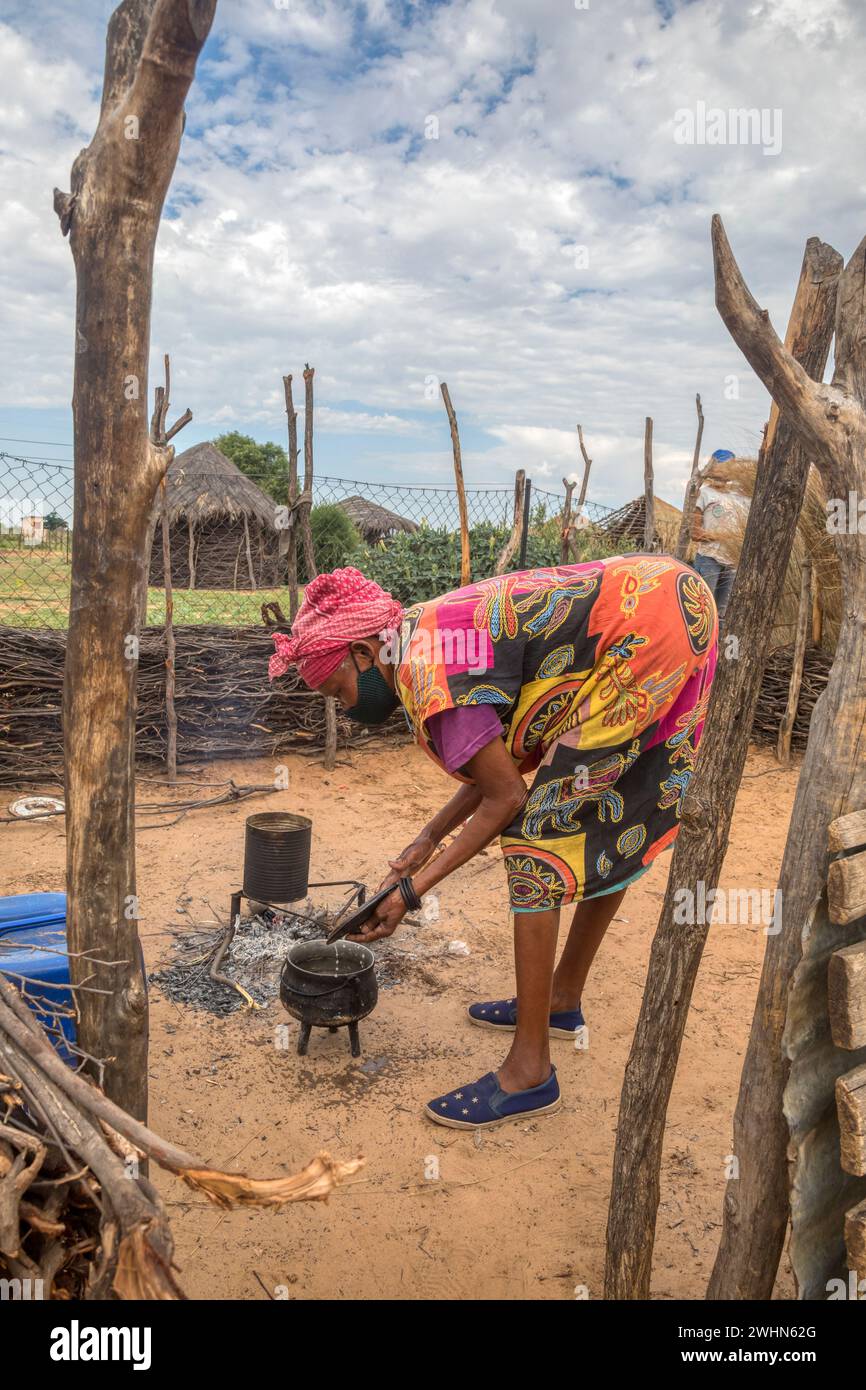 Vieille femme africaine cuisinant dans la cuisine extérieure dans un village africain Banque D'Images