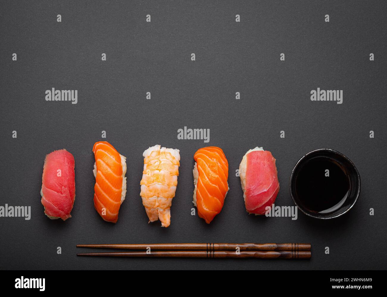 Sushi traditionnel japonais vue de dessus avec sauce soja et baguettes sur fond noir foncé minimal. Sushi au saumon, thon, shr Banque D'Images