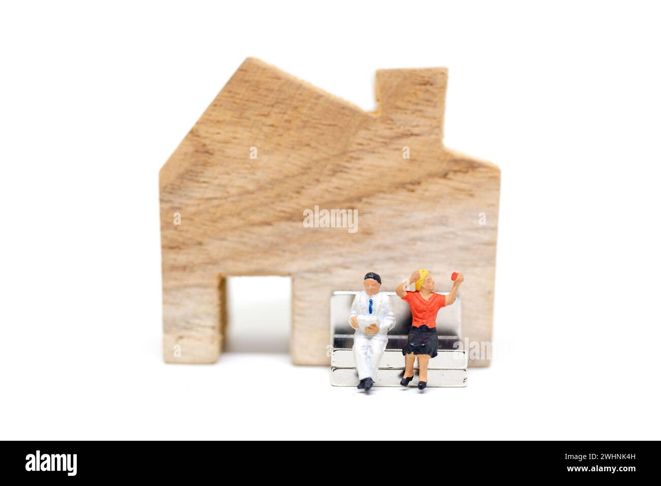 Personnages miniatures : mari et femme assis devant la maison sur fond blanc Banque D'Images