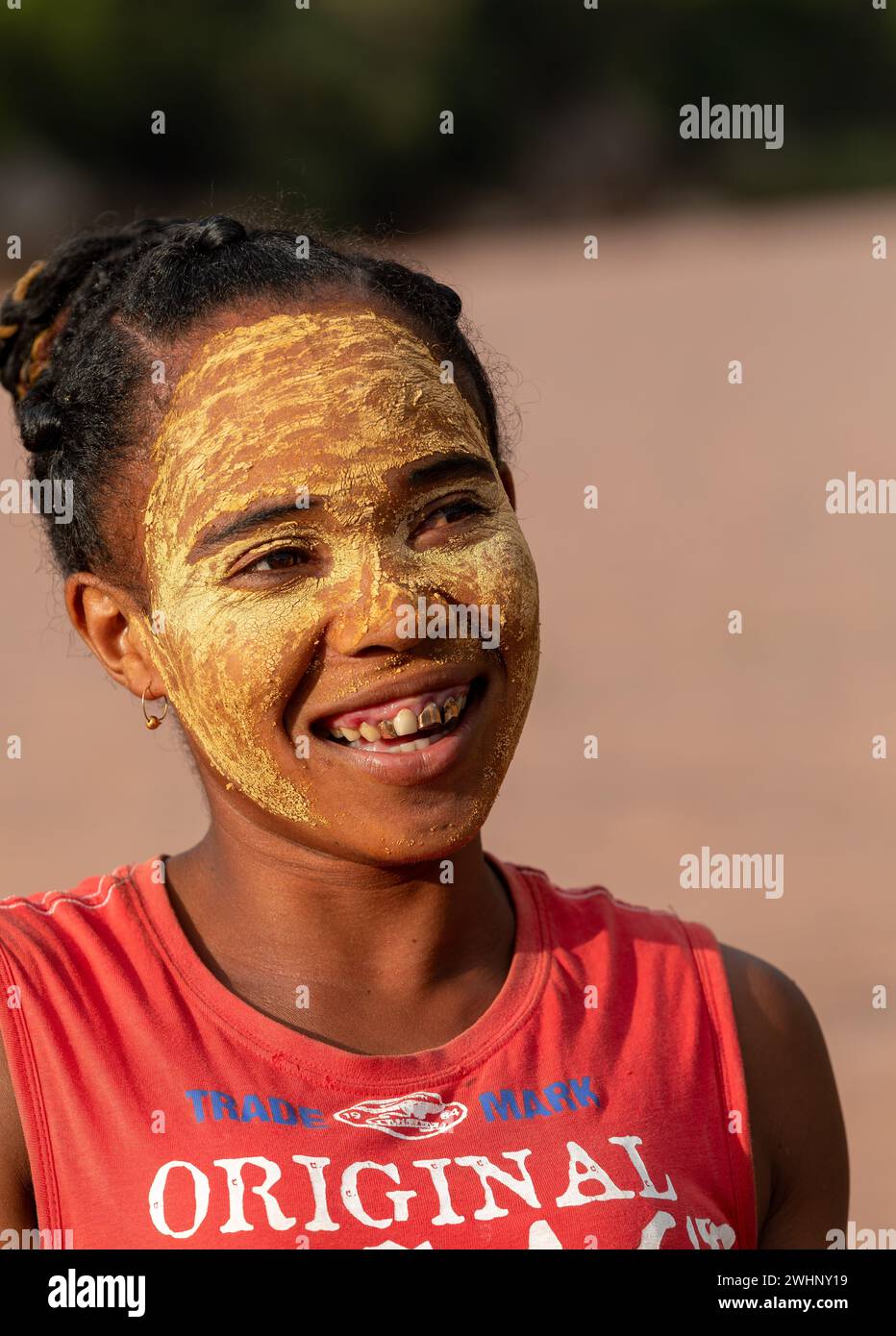 Femme malgache devant sa cabane avec un visage peint traditionnellement. Les femmes malgaches peignent leurs visages pour protéger leurs visages fr Banque D'Images