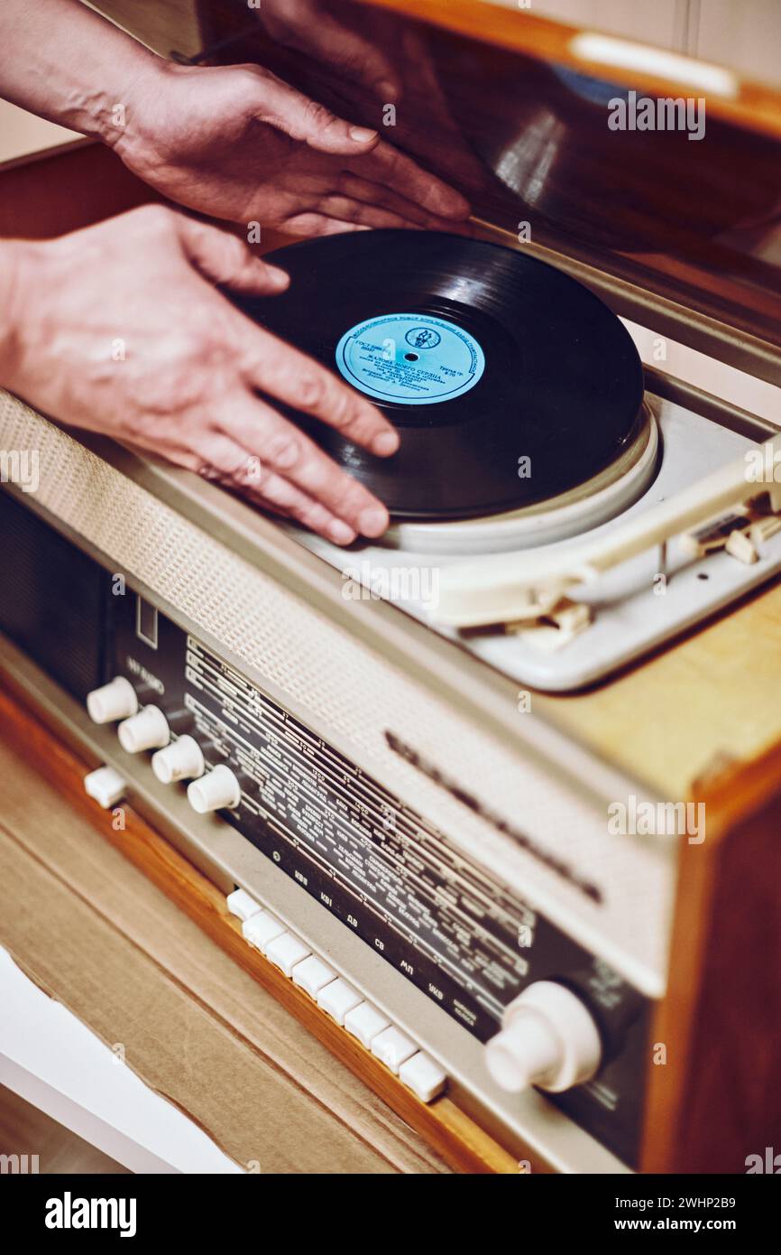 Istra, Russie - 06 septembre 2021 : disque vinyle, tournant sur platine, lecteur de disques Vintage avec radio 60's.. Putti mains homme Banque D'Images