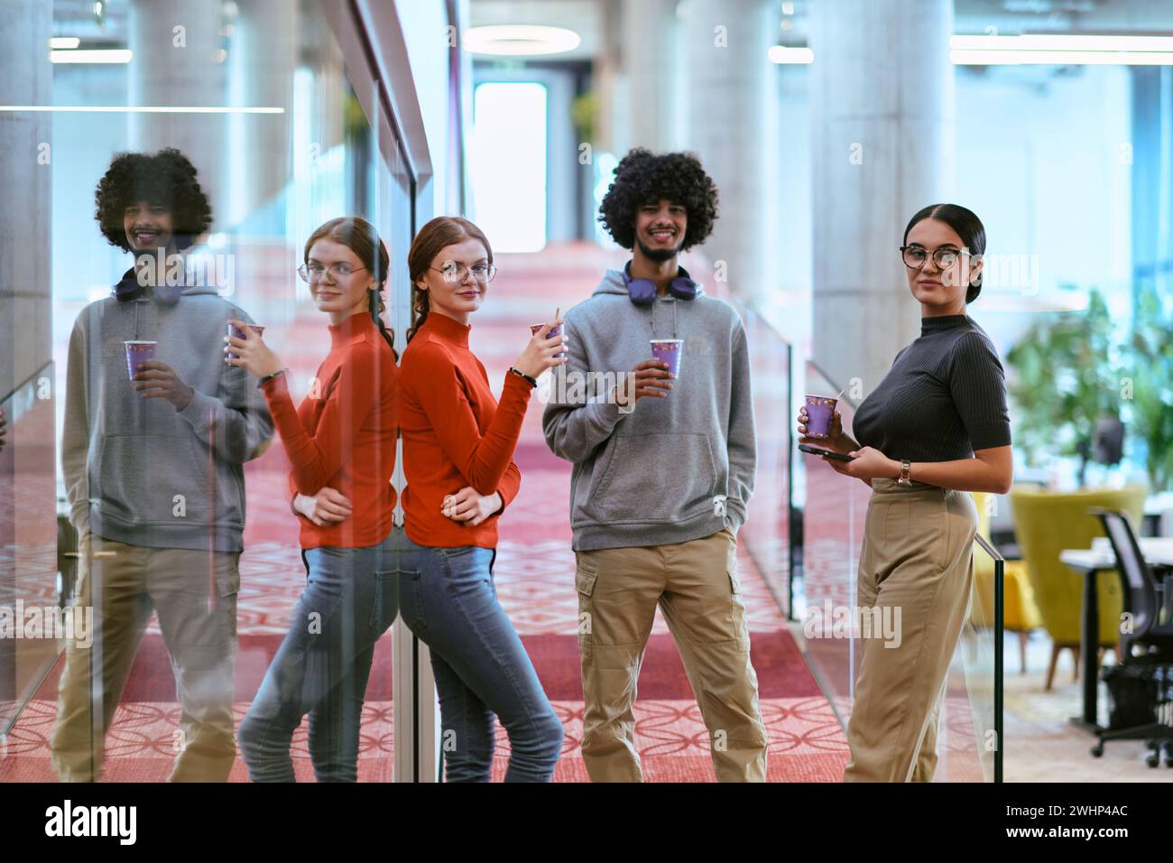 Au milieu des murs de verre modernes d'un bureau de démarrage, un groupe diversifié de collègues, y compris un homme afro-américain, s'engagent dans un Banque D'Images