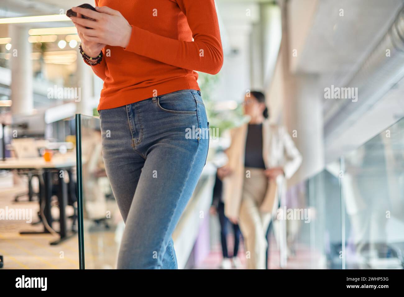 Dans un bureau de start-up moderne dynamique, une femme d'affaires aux cheveux orange frappants est immergée dans son travail à son bureau, incarnant le Banque D'Images